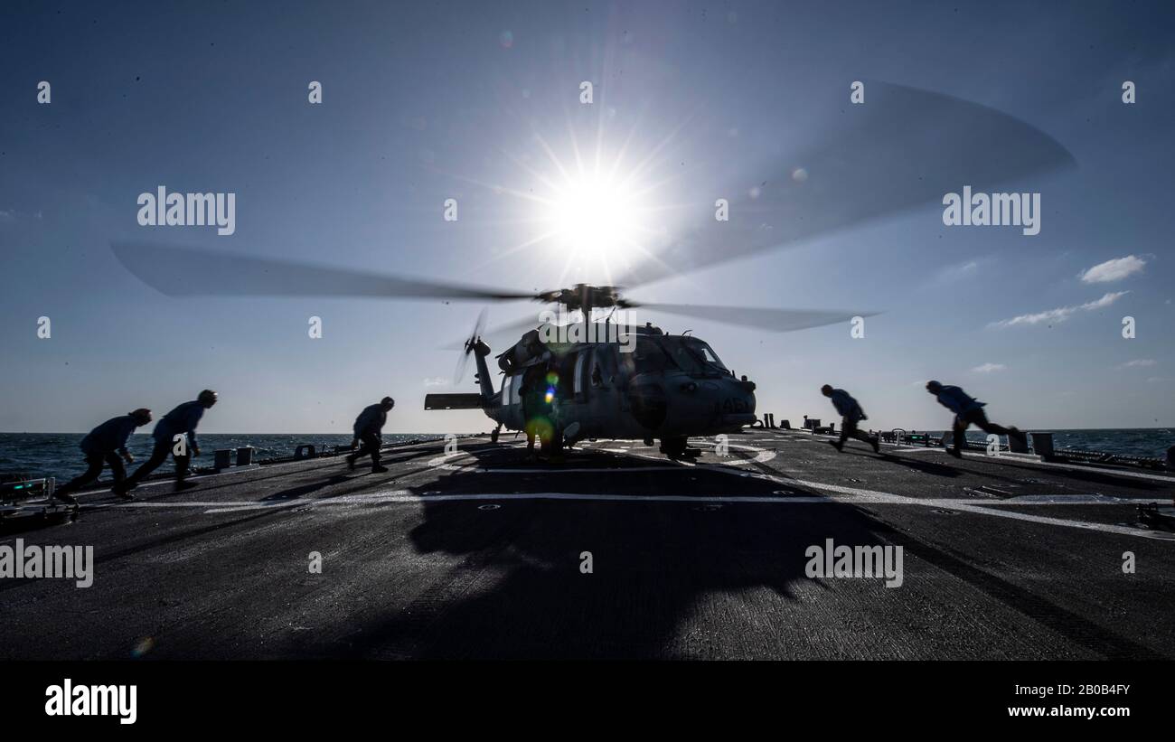 200213-N-TI693-1146 GOLFE ARABIQUE (FÉV 13, 2020) - Les Marins affectés au destroyer de missile guidé USS Carney (DDG 64) sont en position de retirer les cales et les chaînes d'un hélicoptère Sea Hawk MH-60 pendant les opérations de vol, 13 février 2020. Carney est déployé dans la 5ème zone d'opérations de la flotte des États-Unis à l'appui des opérations navales pour assurer la stabilité et la sécurité maritimes dans la région centrale, reliant la Méditerranée et le Pacifique à travers l'océan Indien occidental et trois points stratégiques de starter. (ÉTATS-UNIS Photo marine par Spécialiste Communication de masse 1ère classe Fred Gray IV) Banque D'Images