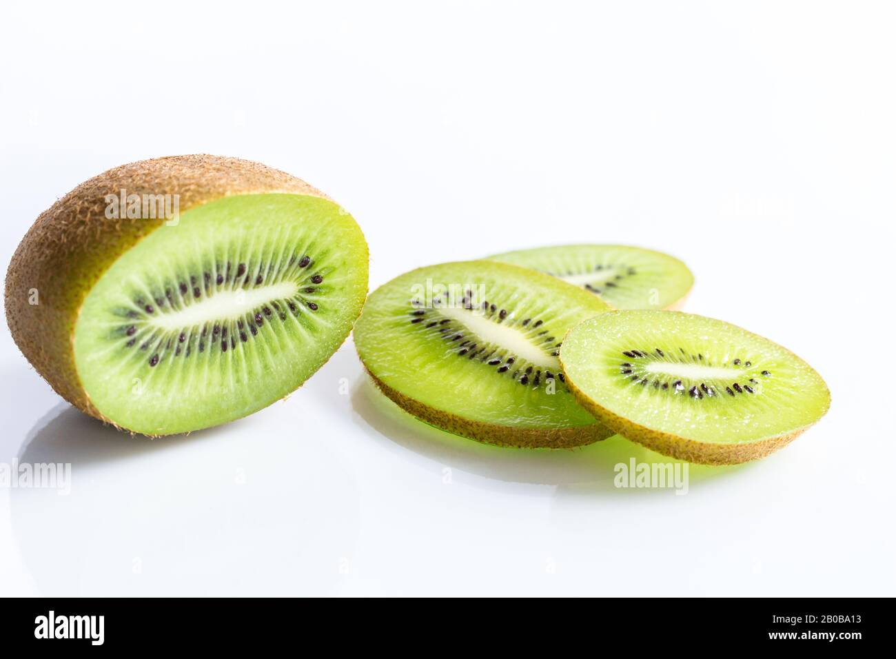 Demi-fruit kiwi et tranches isolées sur fond blanc avec mise au point sélective - photo horizontale Banque D'Images