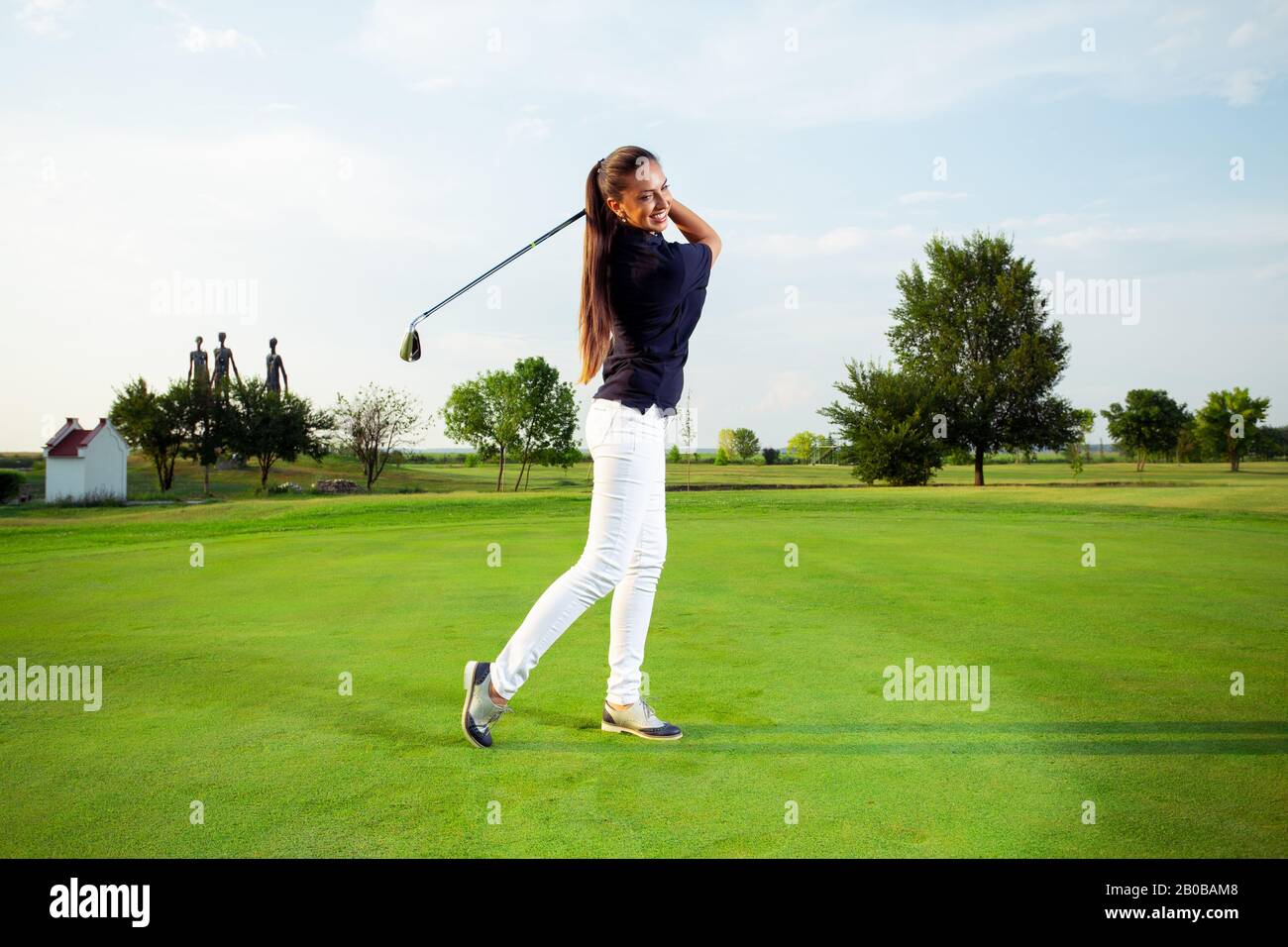 Un golfeur féminin pratique son swing. Elle se prépare à un jeu. Banque D'Images