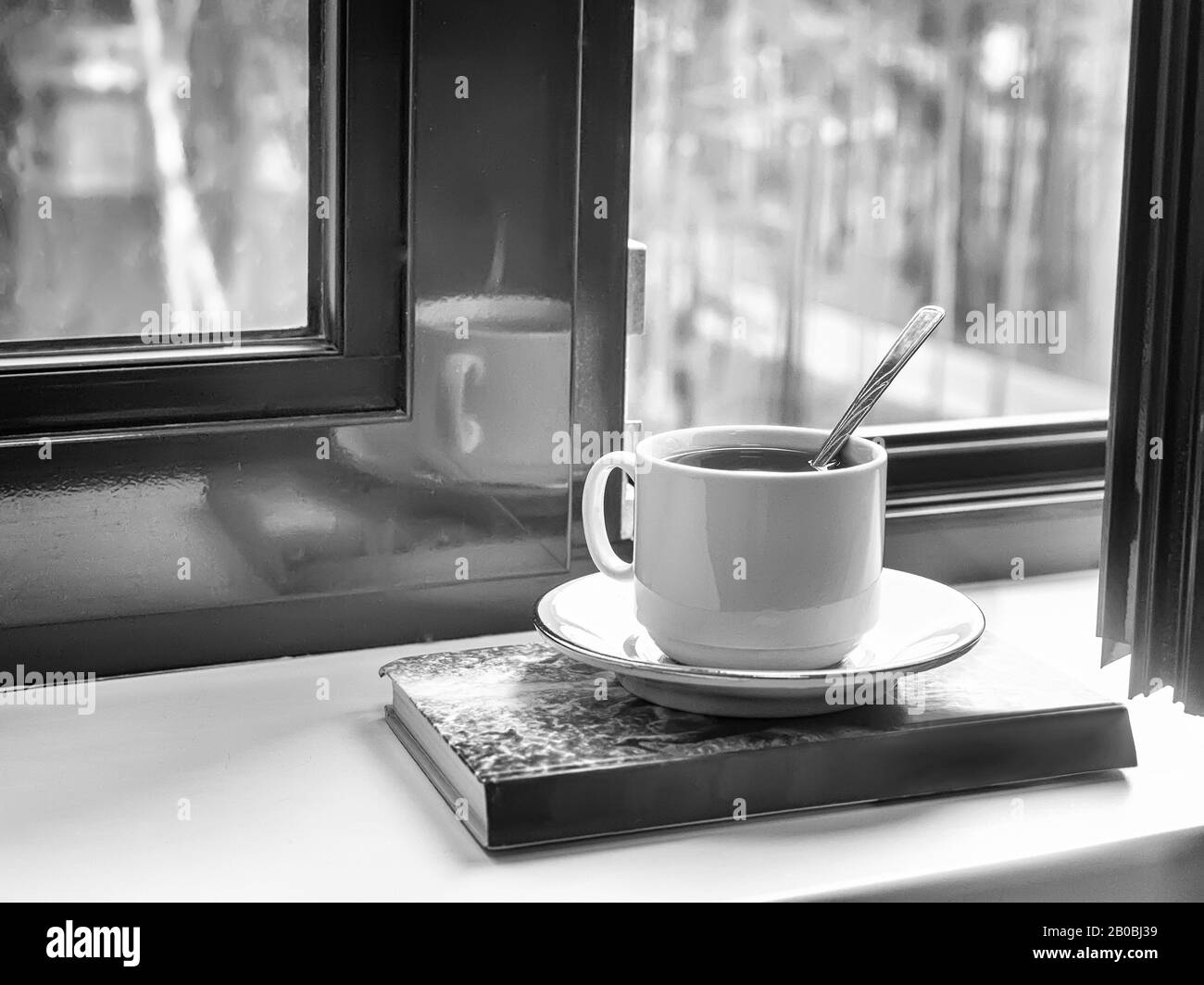 Une tasse de thé et un livre sur le seuil de la fenêtre Banque D'Images