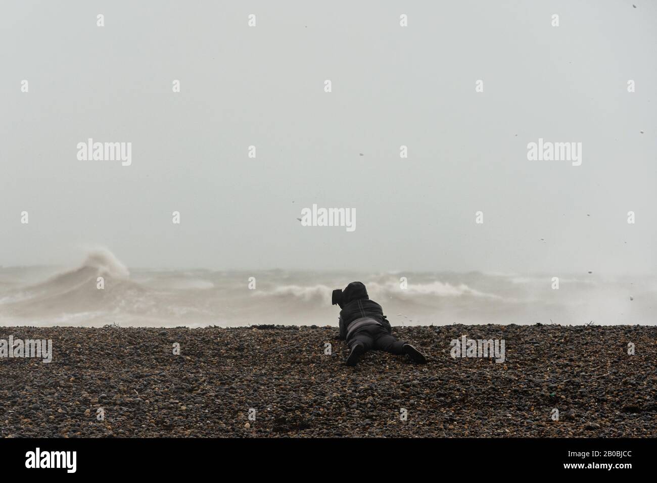 Photographe allongé prenant des photos de vagues massives au large de la côte du Sussex à Newhaven lors de la tempête Ciara le 9 février 2020 Banque D'Images