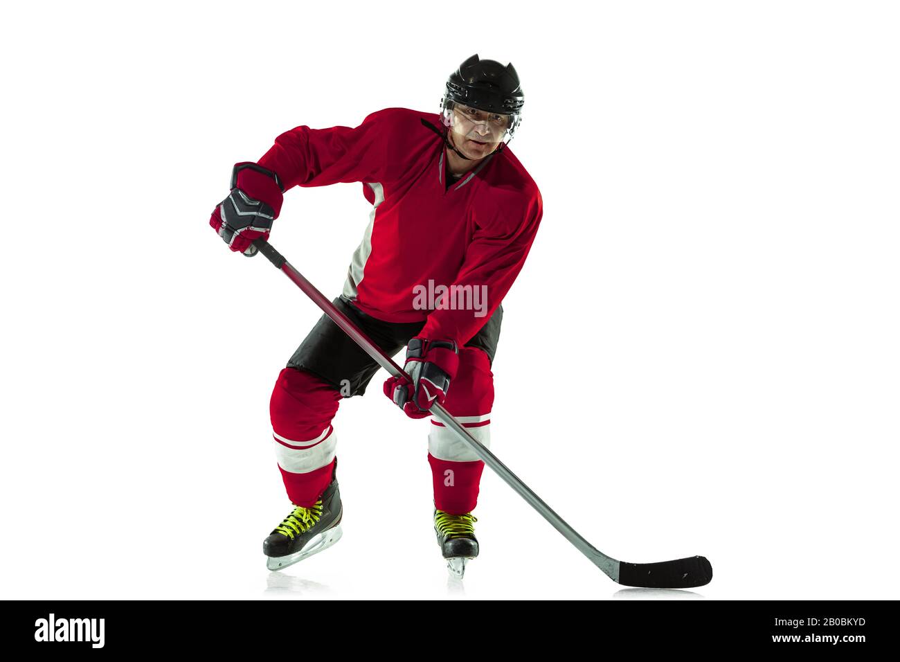 Notation d'un objectif. Joueur de hockey masculin avec le bâton sur la cour de glace et fond blanc. Sportif portant de l'équipement et du casque pratiquant. Concept de sport, mode de vie sain, mouvement, mouvement, action. Banque D'Images