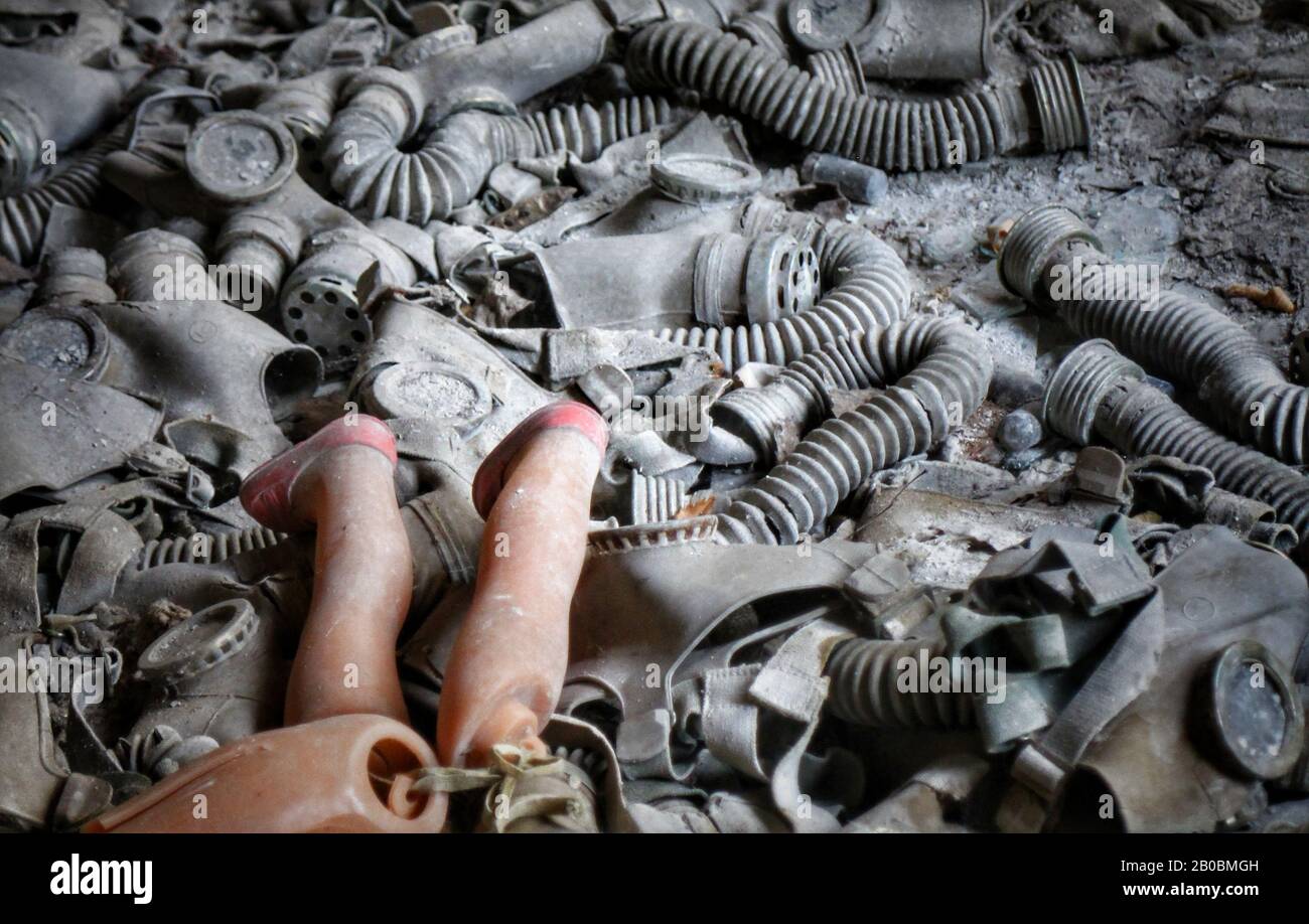 Une poupée cassée sur une pile de masques à gaz de l'ère soviétique dans un bâtiment abandonné à Pripyat, en Ukraine, site du déastre nucléaire de Tchernobyl de 1986. Banque D'Images