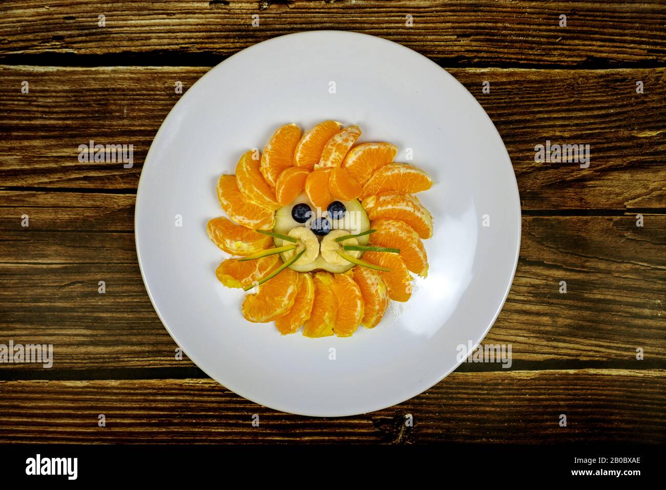 drôle de composition du visage de lion avec des fruits comme le bleuet d'orange sur table en bois . Banque D'Images