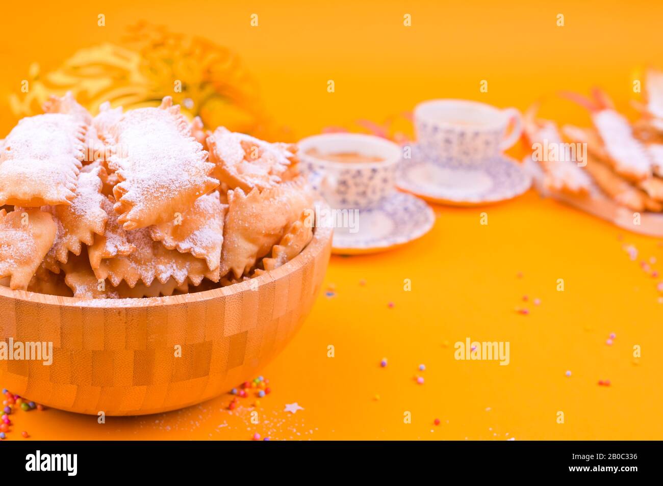 Crostoli, chiacchiere, biscuits et espresso parfumé sur un fond jaune, coloré avec des confettis et décor festif. Café et bonbons pour un carnaval italien traditionnel. Espace de copie Banque D'Images