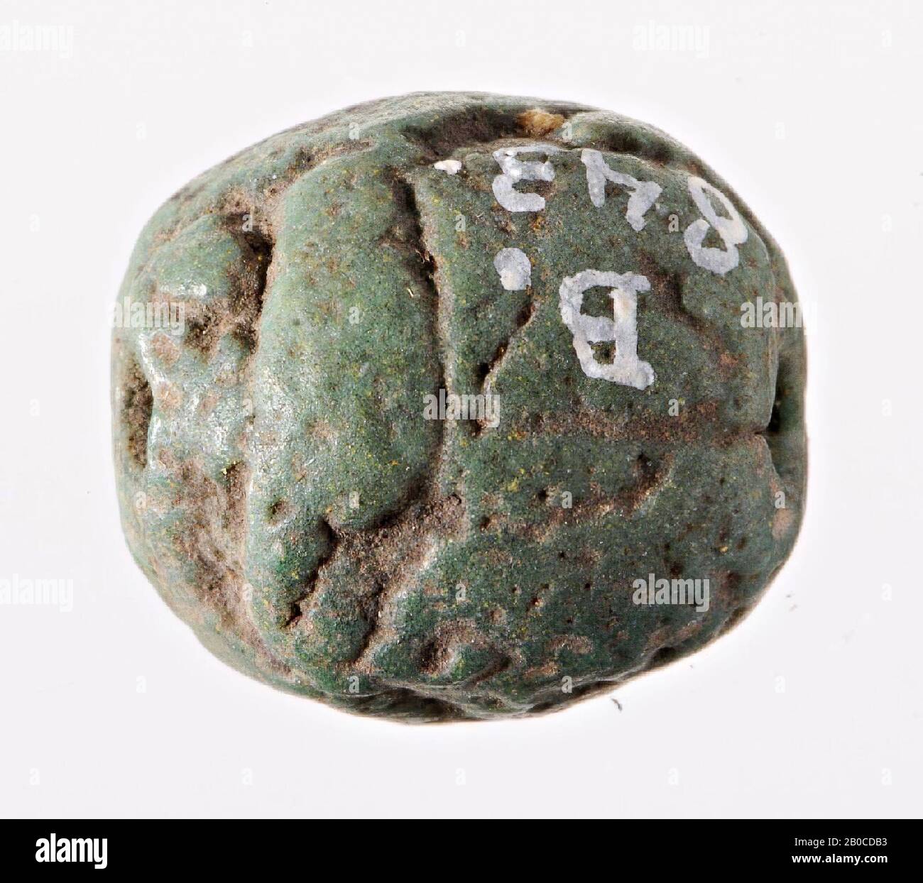 Scarab, Amon, signe moins, Le sceau a la forme d'un scarab stylisé avec peu de détails. La séparation entre la tête et le clypeus, le pronotum et l'elytra a néanmoins été indiquée par des lignes sunken. Les deux côtés ne sont pas traités : ni les jambes ni les rainures décoratives ne sont affichées. Le nom de la déesse Amon ou Amon-Re est placé dans la zone de scellement, limité au-dessus et au-dessous par un signe de mer, de sorte que "aimé par Amon" peut être lu. L'objet est perforé dans le sens de la longueur, phoque, scarabée, foi verte, 1,4 × 1,3 × 0,7 cm, Egypte Banque D'Images