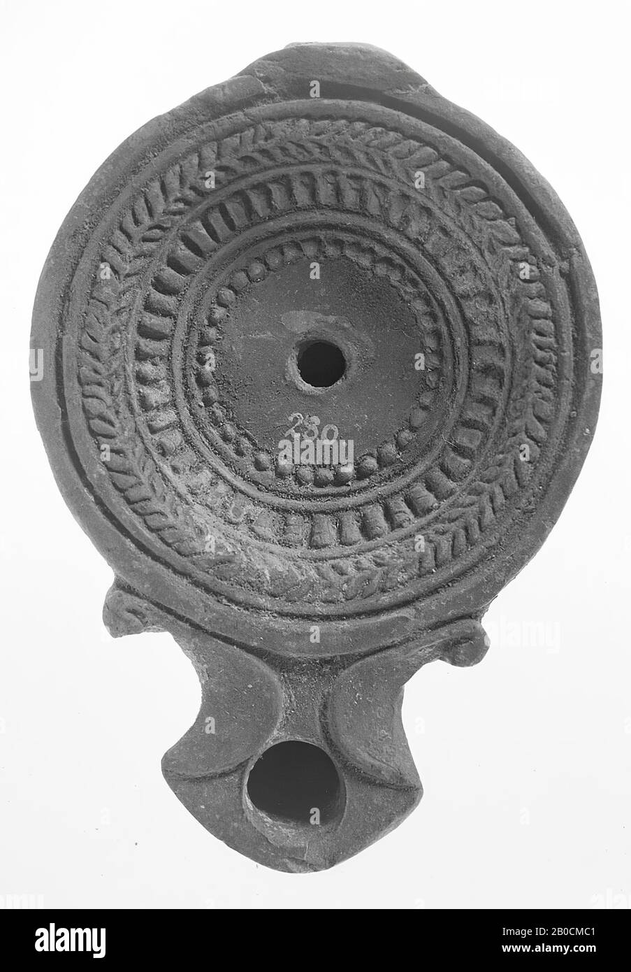 Lampe à huile brunie marron avec corps rond sur une base plate. Le miroir concave est entouré de cercles concentriques encastrés, d'une branche de palmier, d'un kyma et d'un cadre perlé. Le bec court et large avec un grand trou de feu est fortement fermé et encadré de volutes. Le petit trou de remplissage est situé au milieu du miroir., lampe à huile, faïence, terre cuite, 3,5 x 11,2 x 7,8 cm, 2ème siècle après J.-C. 100-200, Asie Banque D'Images
