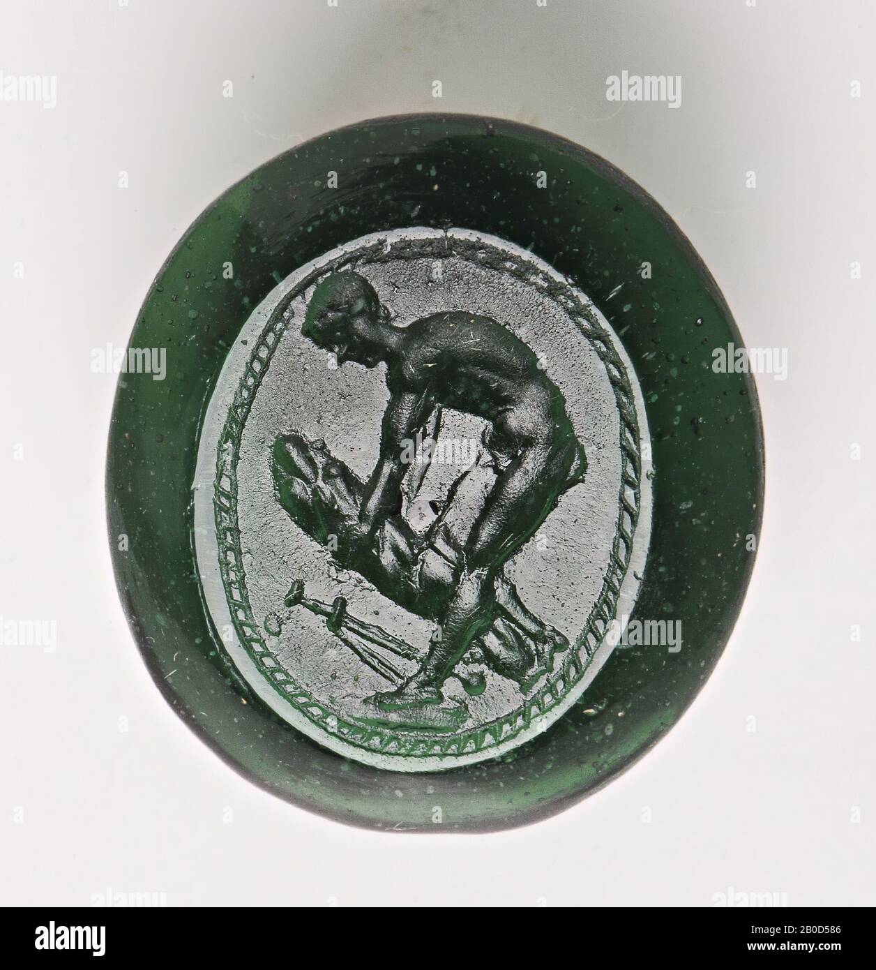 VZ: L'homme essaie de briser un objet non identifié (branche?) Avec son genou droit, une épée se trouve sur le sol, le tout est entouré d'une bande de globules., Gem, intaglio, inconnu, couleur : vert, forme: Ovale, traitement: bord coupé à l'avant et à l'arrière par rapport au centre du bord., 14 x 17 x 5,5 mm Banque D'Images