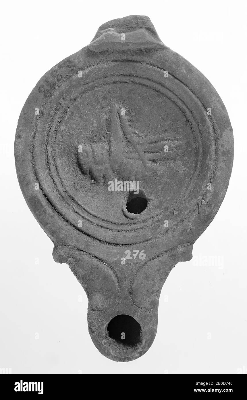 Une lampe à huile rouge vernie avec un corps rond sur un socle encastré. Le miroir concave est entouré de cercles concentriques encastrés et est décoré avec une image relief d'une sauterelle. Le bec court et large avec un grand trou de feu est décoré de volutes et rond fermé. Le petit trou de remplissage est situé sous la figure., lampe à huile, faïence, terre cuite, 3.2 x 10.2 x 6.5 cm, 1ère et 2ème siècle AD. 1-200, Asie Banque D'Images