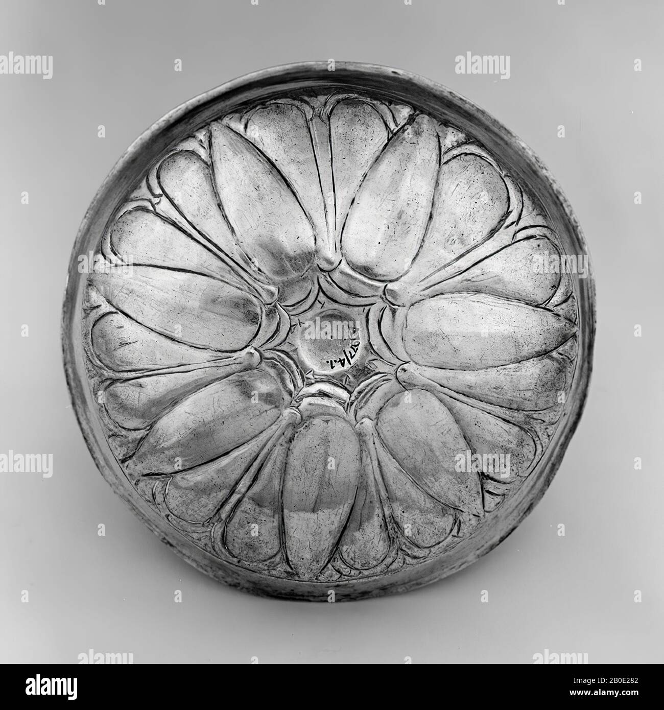Un petit bol en argent avec un mur en forme de S. Le bol a un fond omphallos et un mur régulier très mince. Le fond est décoré d'une rosette, accentuée de lignes gravées. La rosette a sept feuilles complètes qui courent en un point. Deux feuilles arrondies sont visibles entre chaque feuille. C'est probablement une représentation d'une fleur de lotus. La décoration peut être vue à l'intérieur et à l'extérieur., vaisselle, métal, argent, H 4.1 cm, D 14 cm, Achemenid Période 500-331 BC, Iran Banque D'Images
