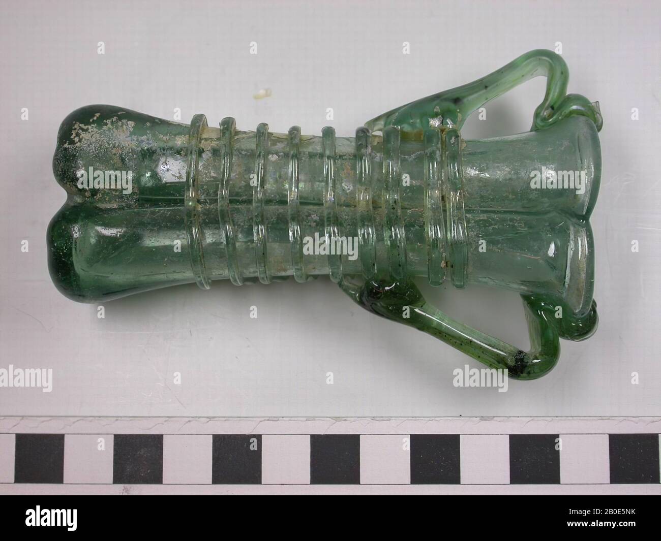 Double clignotement de verre vert clair. La bouteille comporte quatre ouvertures et deux oreilles verticales. Le corps est enroulé avec un fil de verre., vaisselle, verre, L 10 cm, Liban Banque D'Images