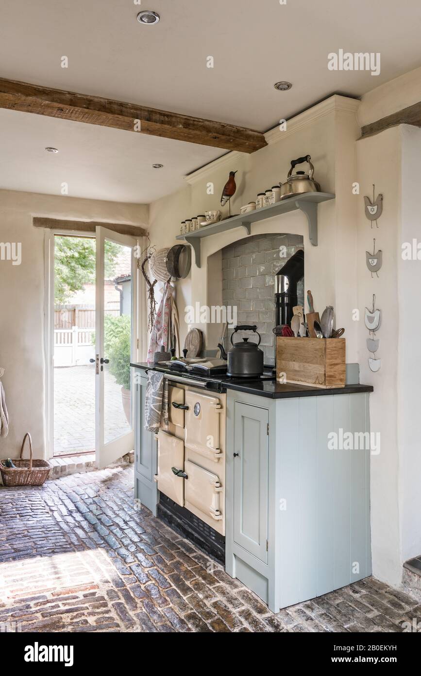 Cuisine équipée de bleu clair avec sol en pavés Rayburn dans la cuisine peinte à Farrow & ball's Matstick avec sol pavé d'origine. Banque D'Images