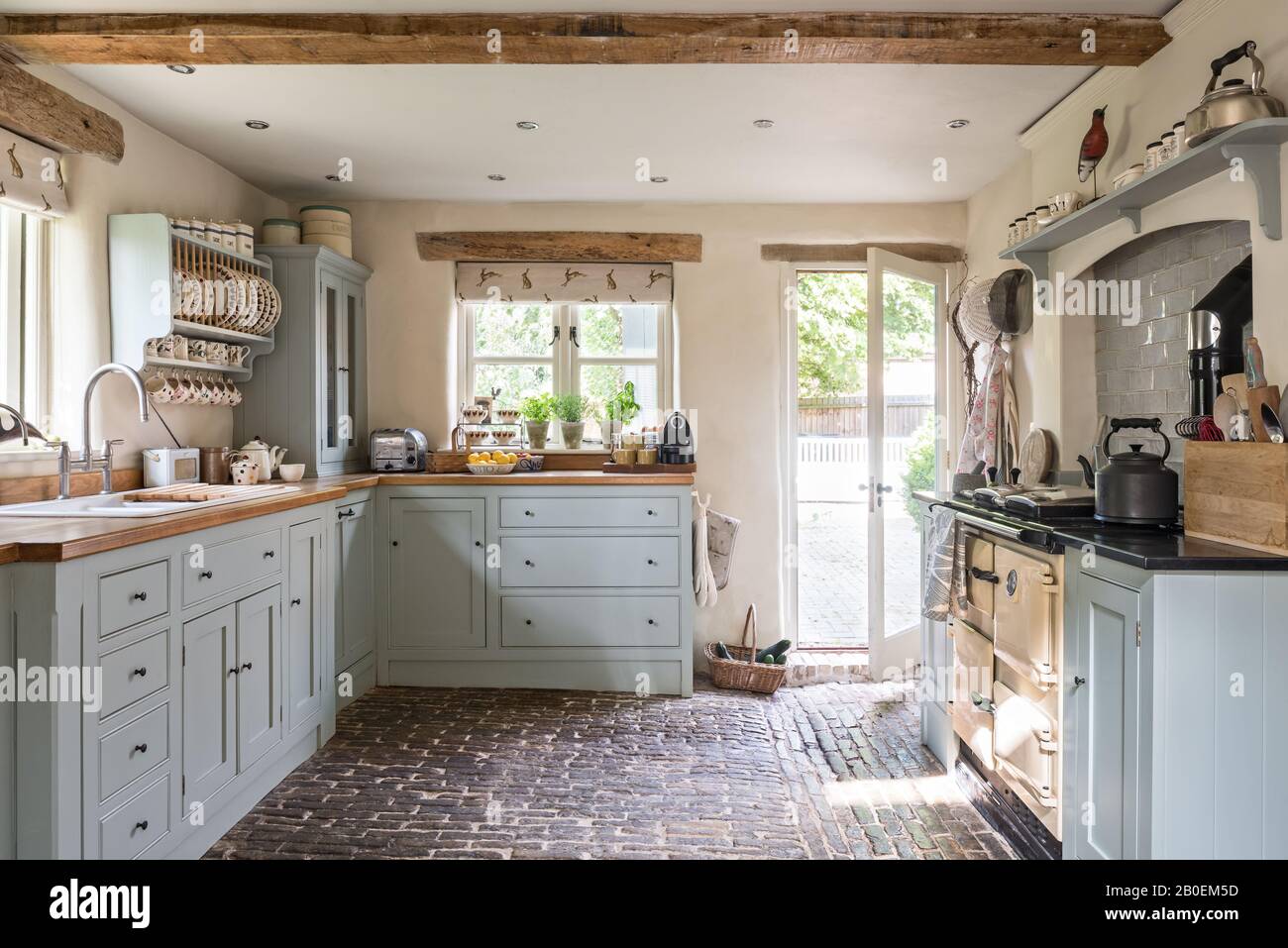 Cuisine équipée de bleu clair avec sol en pavés Rayburn dans la cuisine peinte à Farrow & ball's Matstick avec sol pavé d'origine. Banque D'Images
