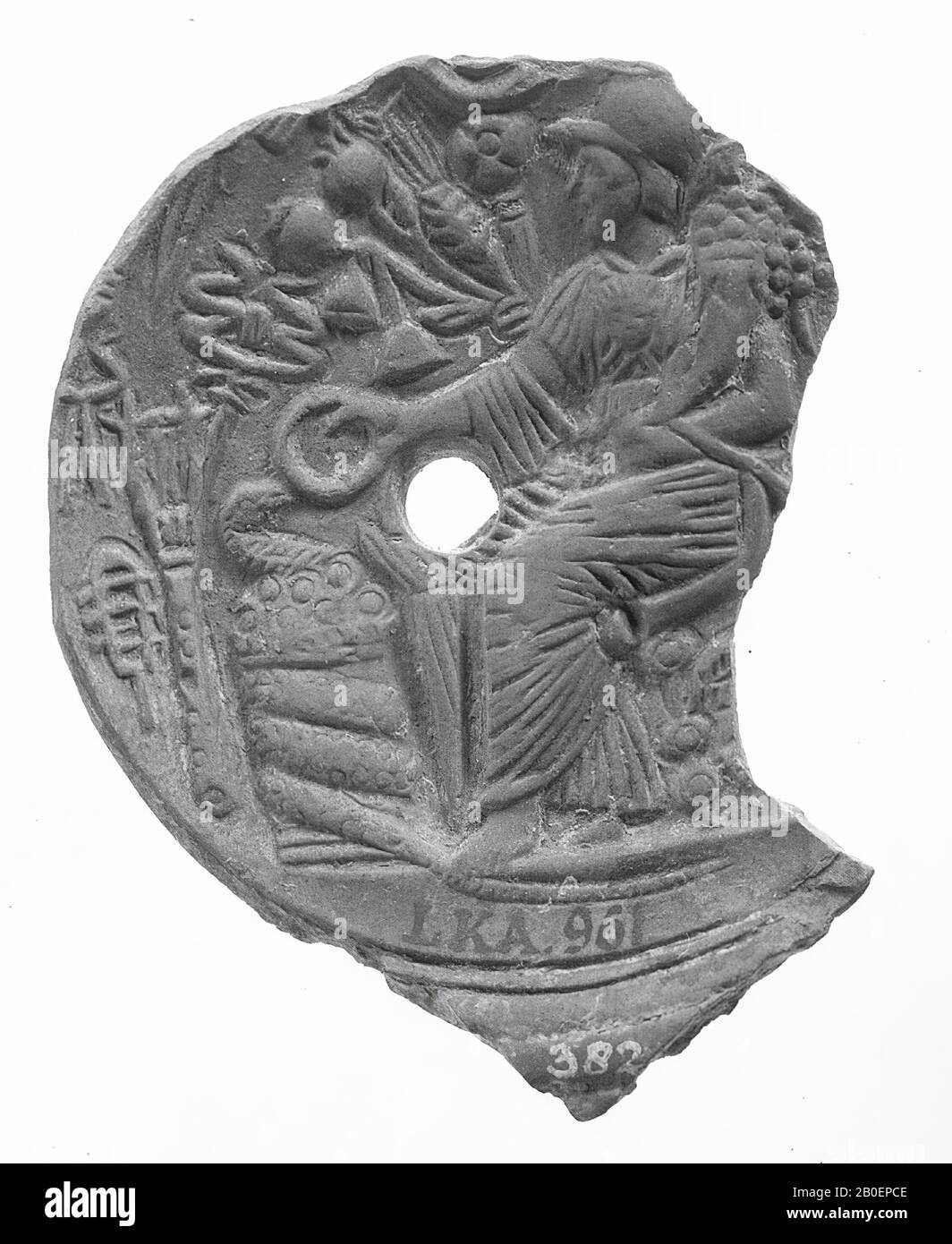 Fragment d'une lampe à huile vernie rouge. Le miroir était entouré de cercles concentriques et est orné d'une image relief d'une déesse hémérée assise avec une cornucopie dans l'un, et d'une patera dans l'autre main, qu'elle court un serpent serpentin. Elle est entourée de toutes sortes de fruits et de fleurs comme des bulbes de pavot et des oreilles de maïs. Le petit trou de remplissage est au centre du spectacle., lampe à huile, poterie, terre cuite, 1,1 x 6,9 x 5,2 cm, 1ère et 2ème siècle AD. 1-200, Turquie Banque D'Images