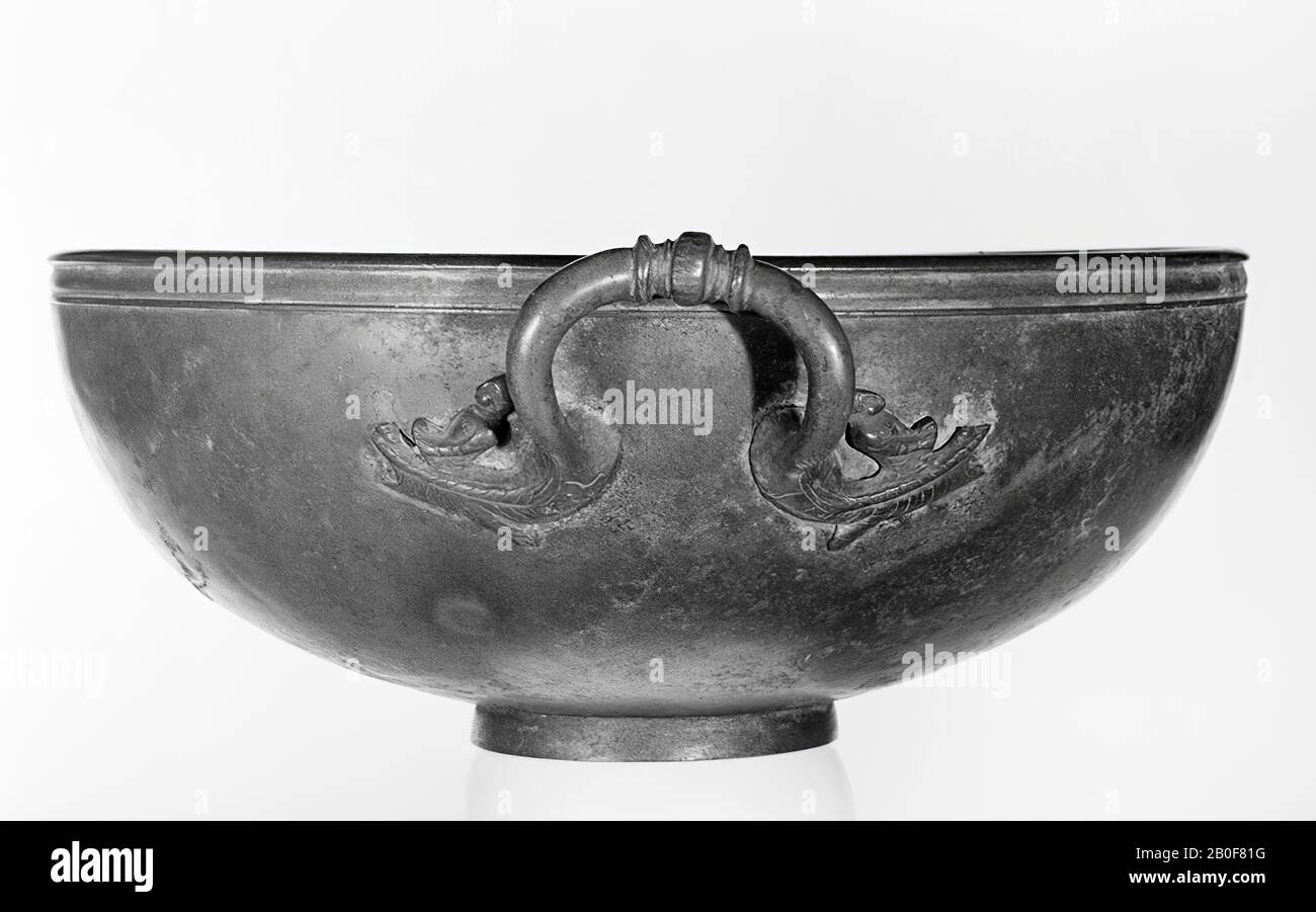 Joli grand bassin en bronze sur le stand dans lequel le fond est fortement tordu, petits cercles de tournage à l'intérieur. Paroi incurvée avec une arête profilée fine, qui est épaississant de manière anguleuse à l'intérieur. 2 oreilles opposées en forme d'oméga soudées en relief sur les deux côtés avec un bateau stylisé avec rameur. Patine verdâtre. Le bassin est préservé exceptionnellement bien. Importer pièce de Italia. Au pied le grafitto: I * (= étoile à 6 armés) V, vaisselle, lavabo, lavabo, métal, bronze, hauteur: 16 cm, Roman 50-100 AD, Pays-Bas, Gueldre, Nimègue, Nimègue Banque D'Images