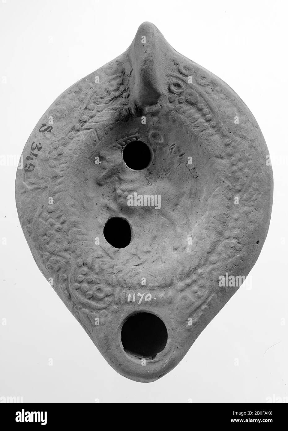 Une lampe de terre rouge clair avec un corps de forme ovale sur une base ronde. Le miroir rond est entouré d'une branche de palmiers et décoré avec un cheval debout entouré de feuilles avec au-dessus et au-dessous d'un trou de remplissage. L'épaule est décorée avec des tendrils. Le bec court et arrondi est doté d'un grand trou d'incendie. La poignée fixée verticalement s'étend sur la base en bas. Marque: Lettres grecques floues, lampe à huile, faïence, terre cuite, 3.8 x 8.9 x 6.5 cm, 4ème, 5ème et 6ème siècle AD. 300-600, Asie Banque D'Images