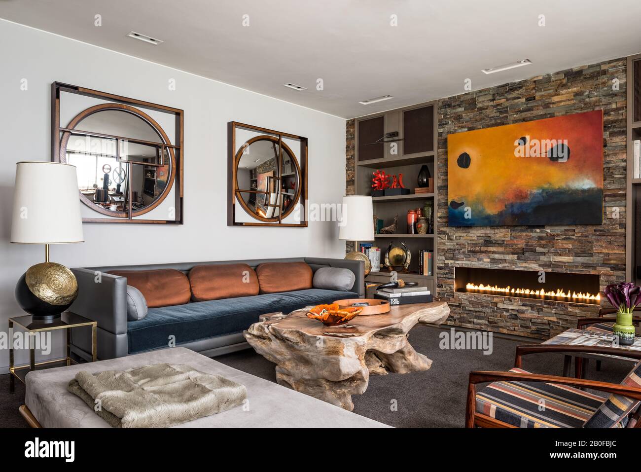 Mur doublé d'ardoise avec table basse en bois massif, lampes anciennes et miroirs de Holly Hunt. Banque D'Images