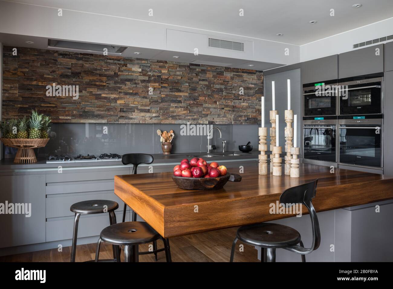 Bar à petit-déjeuner en teck avec murs ornés d'ardoise dans la cuisine de l'appartement moderne de West London. Banque D'Images
