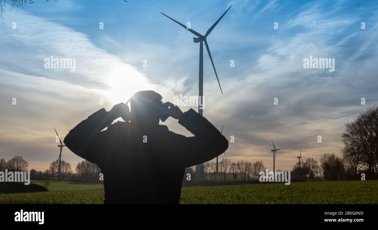 Ingénieur debout devant une éolienne pendant le coucher du soleil. Banque D'Images