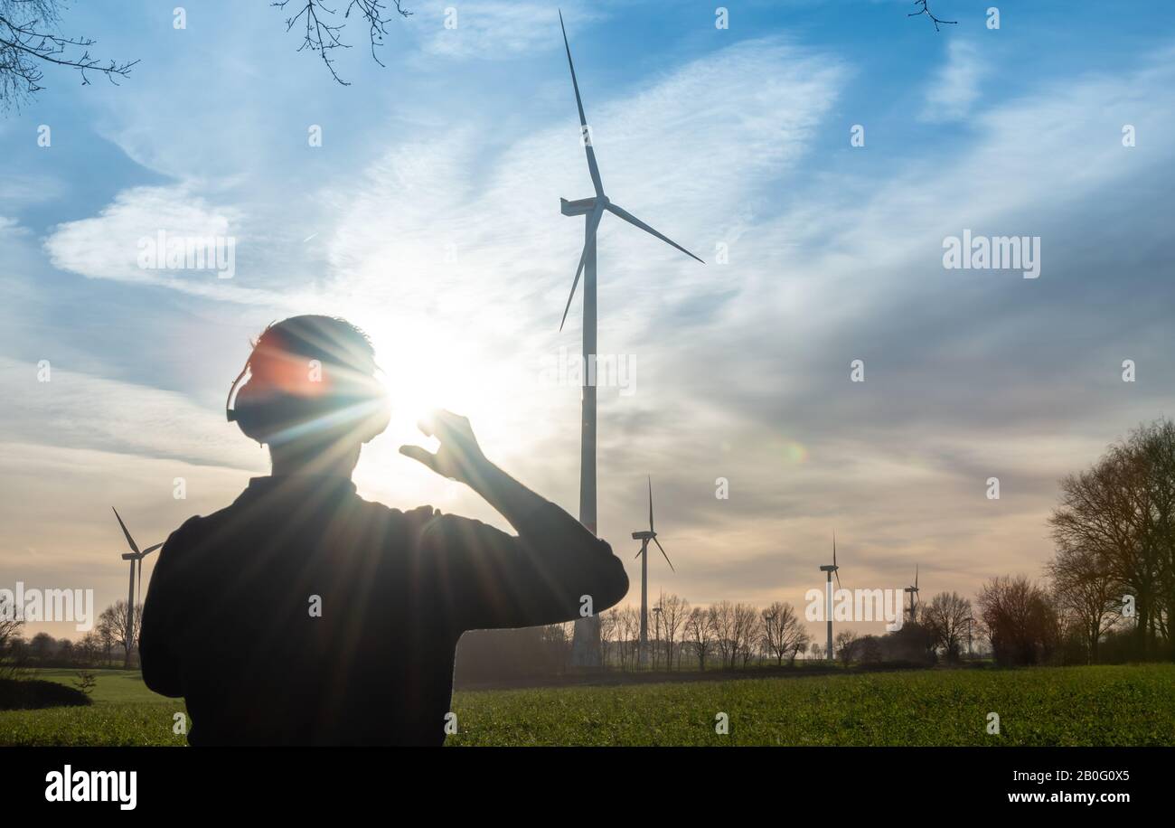 Ingénieur debout devant une éolienne pendant le coucher du soleil. Banque D'Images