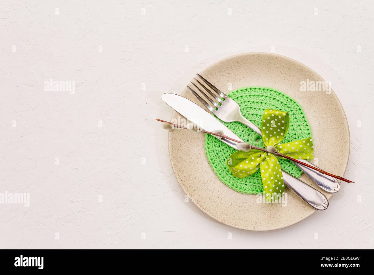 Réglage de la table de Pâques sur fond de putty blanc texturé. Modèle de carte vacances de printemps. Couverts, serviette tricotée, noeud, sceaux saules, espace de copie, vie supérieure Banque D'Images
