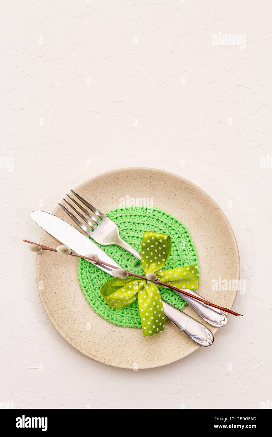 Réglage de la table de Pâques sur fond de putty blanc texturé. Modèle de carte vacances de printemps. Couverts, serviette tricotée, noeud, sceaux saules, espace de copie, vie supérieure Banque D'Images
