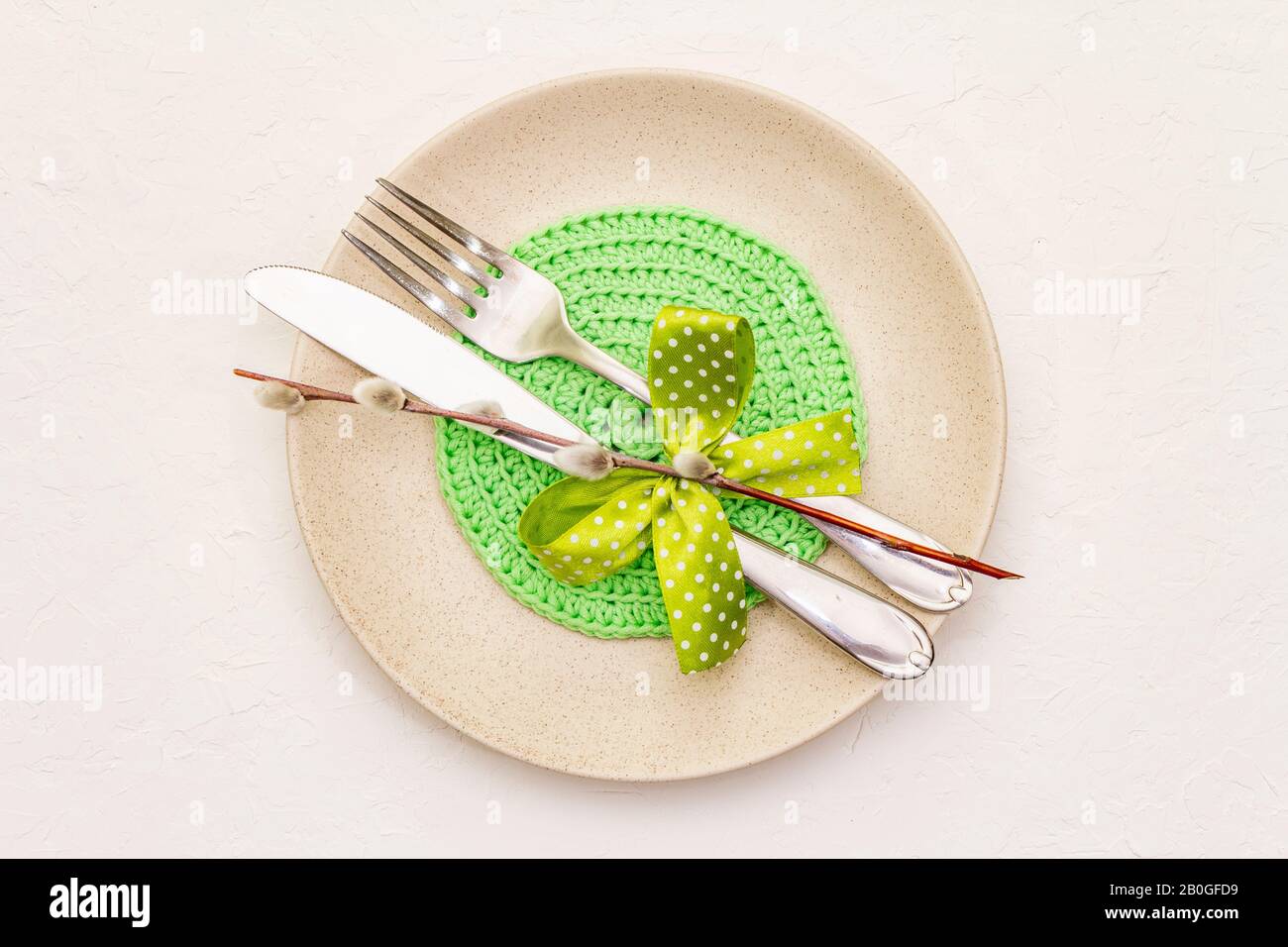Réglage de la table de Pâques sur fond de putty blanc texturé. Modèle de carte vacances de printemps. Couverts, serviette tricotée, noeud, sceaux saules, espace de copie, vie supérieure Banque D'Images