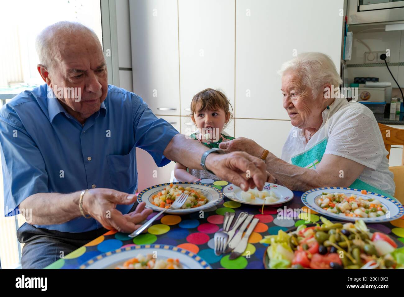 Grands-parents mangeant avec petite-fille dans la cuisine Banque D'Images