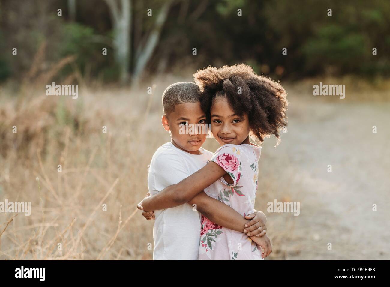 Portrait de trois frères et sœurs baignés de soleil souriant à l'appareil photo Banque D'Images