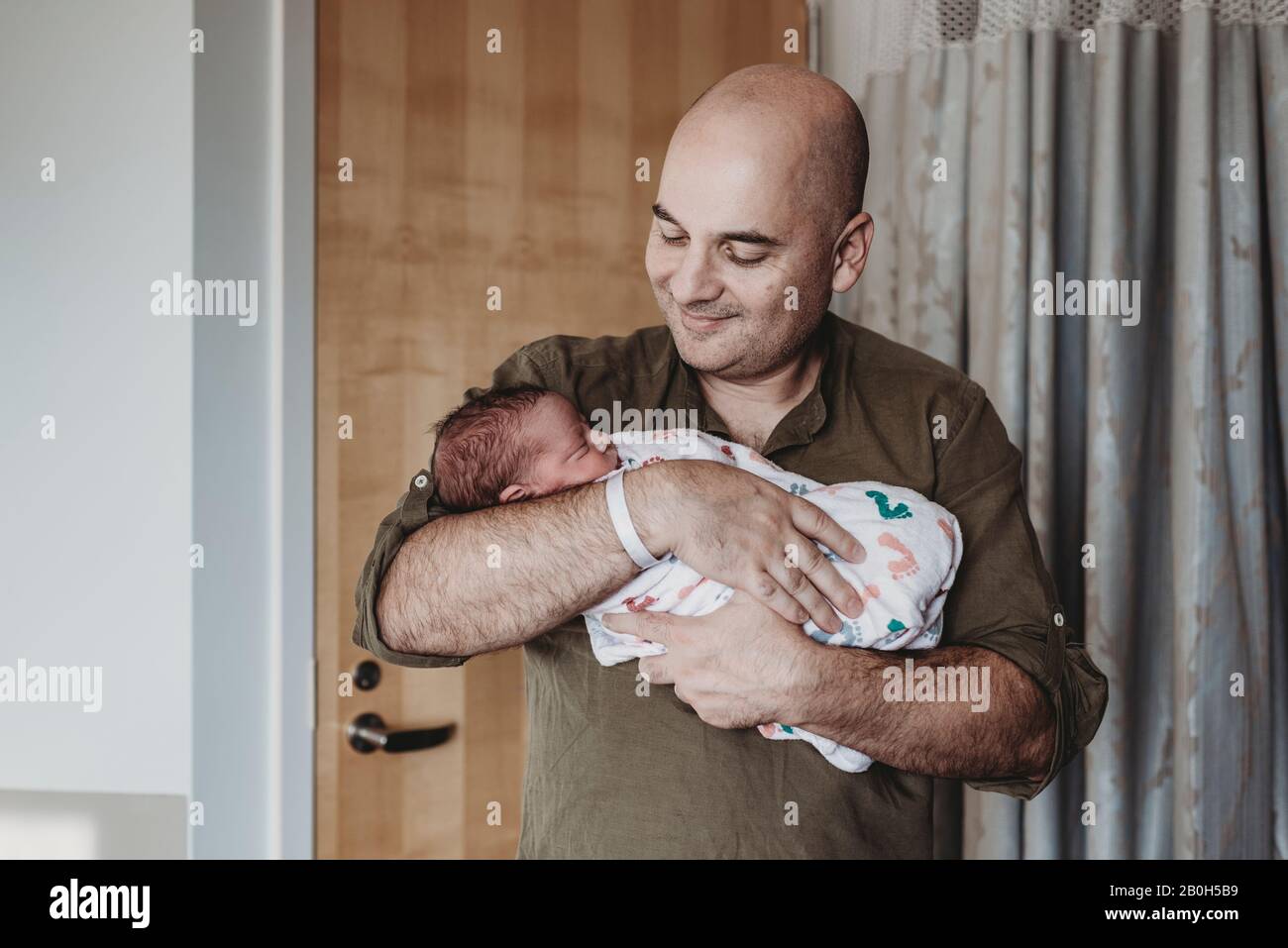 Père heureux tenant un nouveau-né enveloppé dans des couvertures à l'hôpital Banque D'Images