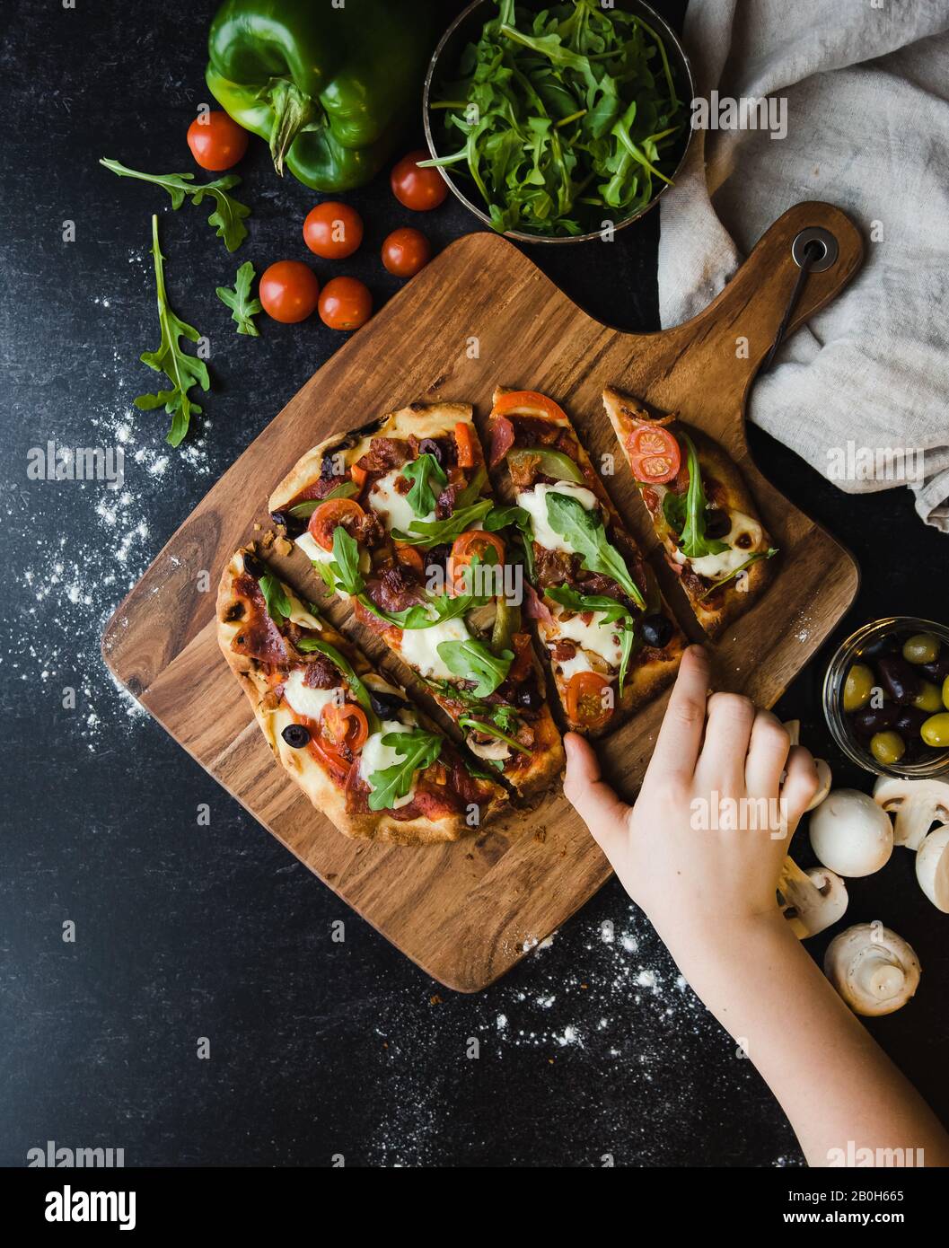 Vue de dessus de la main pour une tranche de pizza faite à la main sur un panneau de bois. Banque D'Images