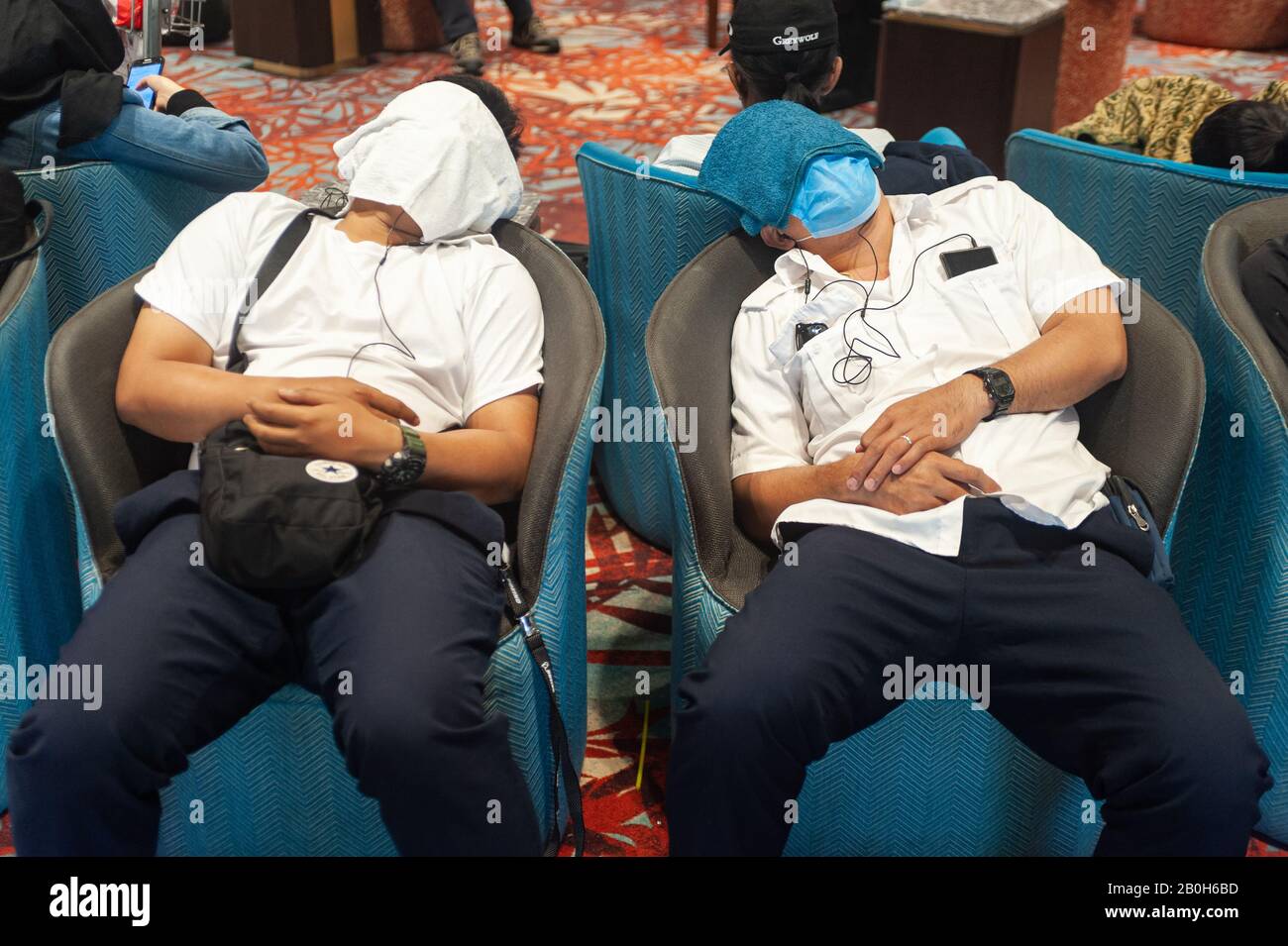 31.01.2020, Singapour, Singapour - Deux voyageurs aériens ont couvert leur visage avec des serviettes et dorment dans des fauteuils dans la zone d'arrivée de Termi Banque D'Images