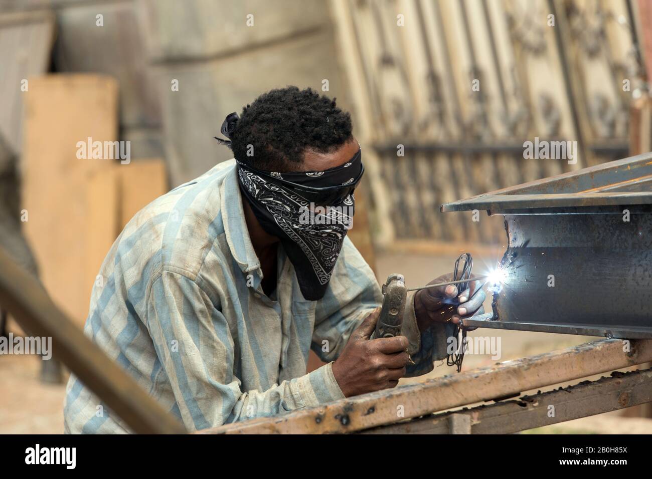 07.11.2019, Adama, Oromiyaa, Ethiopie - un serrurier soudure des portes et des grilles ensemble dans la rue à l'aide d'une machine de soudage électrique. Il porte du soleil Banque D'Images