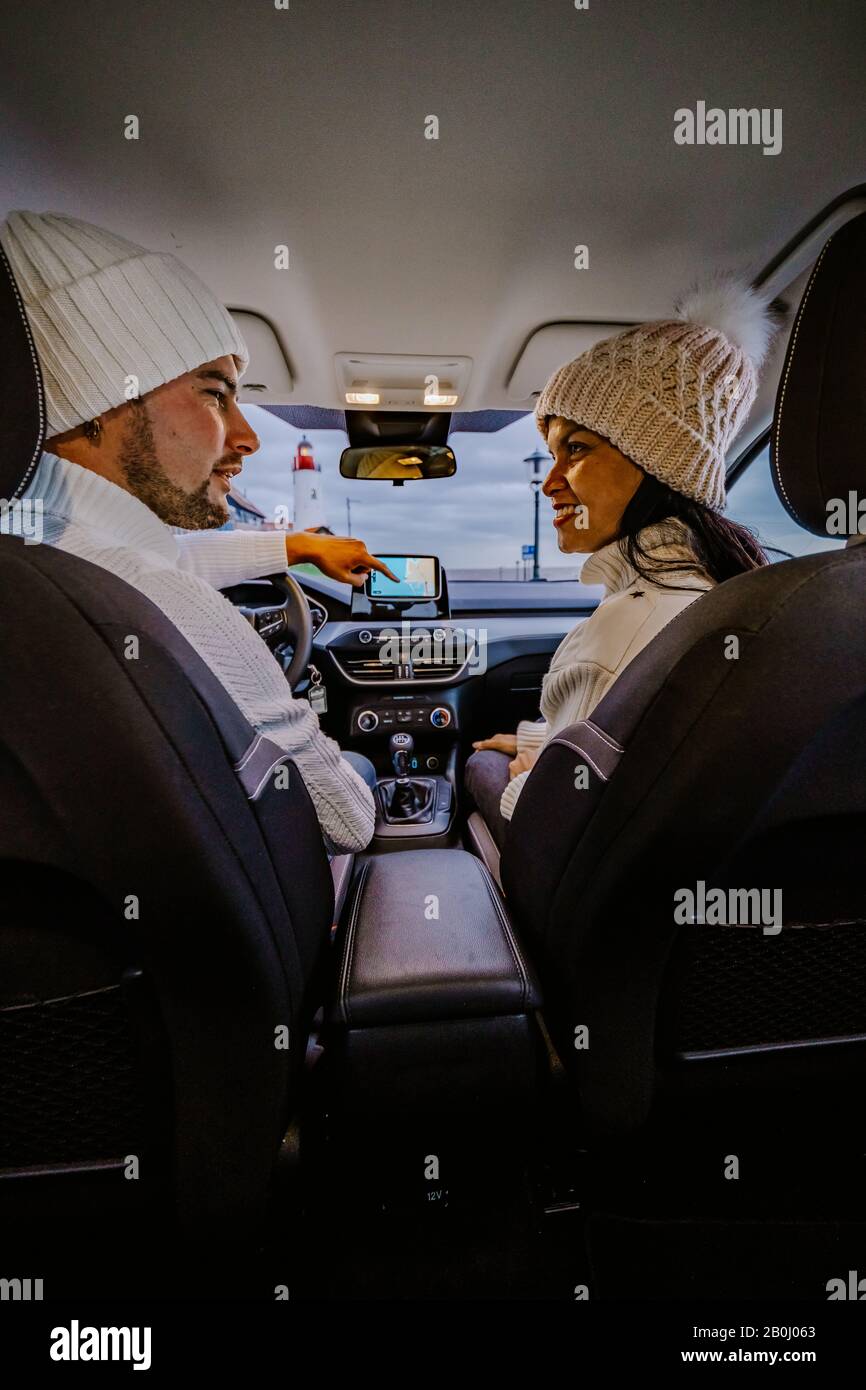 Vue arrière des jeunes couples en utilisant une carte sur un voyage pour les directions. Jeune homme et femme lisant une carte en étant assis dans une voiture. Banque D'Images