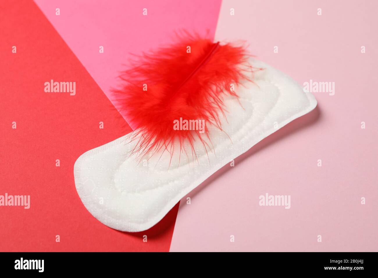 Coussin sanitaire et plume sur fond multicolore, gros plan Banque D'Images