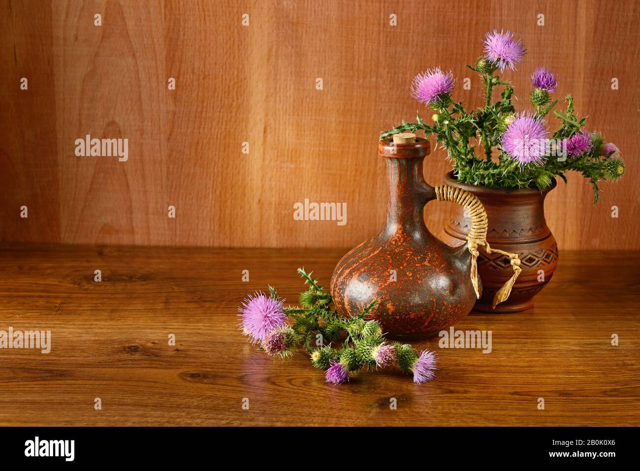 Fleurs et huile de chardon sur fond de bois. Banque D'Images