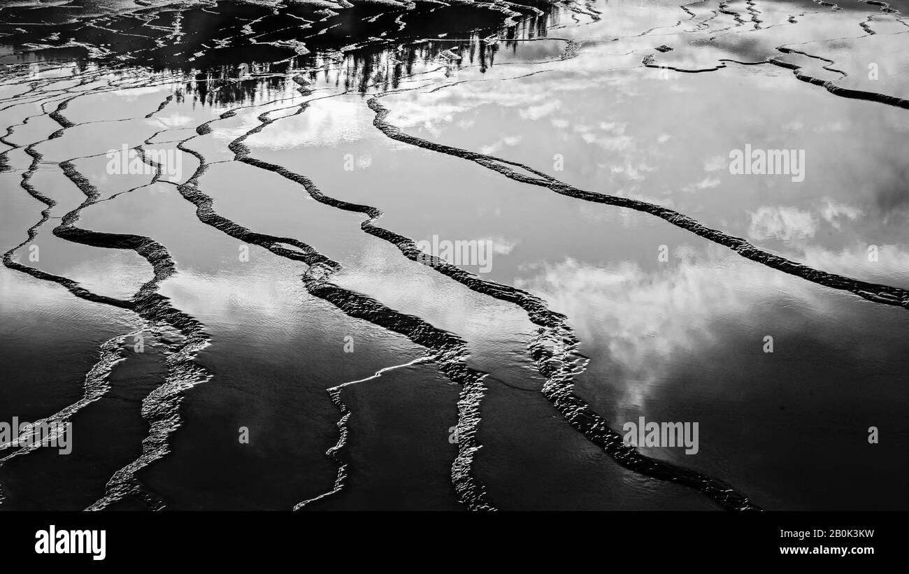 Surfaces rocailleuses lisses reflétant le ciel et les arbres. Texture de la surface rocheuse. Banque D'Images