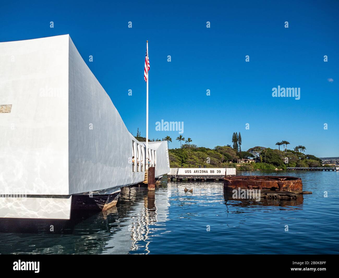 Arizona Memorial à Pearl Harbor se reflète dans l'eau miroir en dessous avec le ciel bleu au-dessus. Banque D'Images