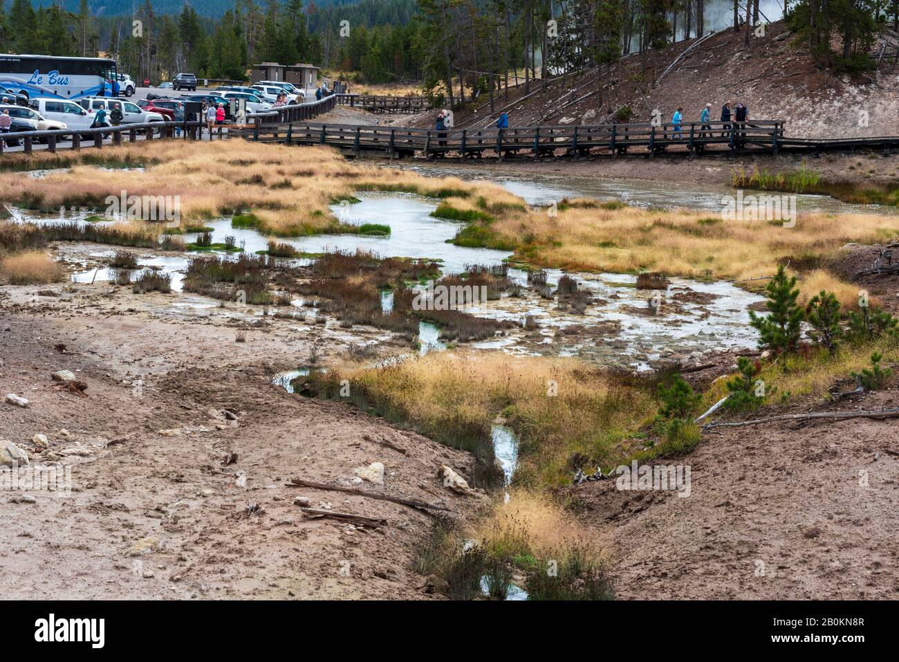 Bus et voitures dans le parking, touristes marchant autour de grandes sources d'eau chaude. Banque D'Images