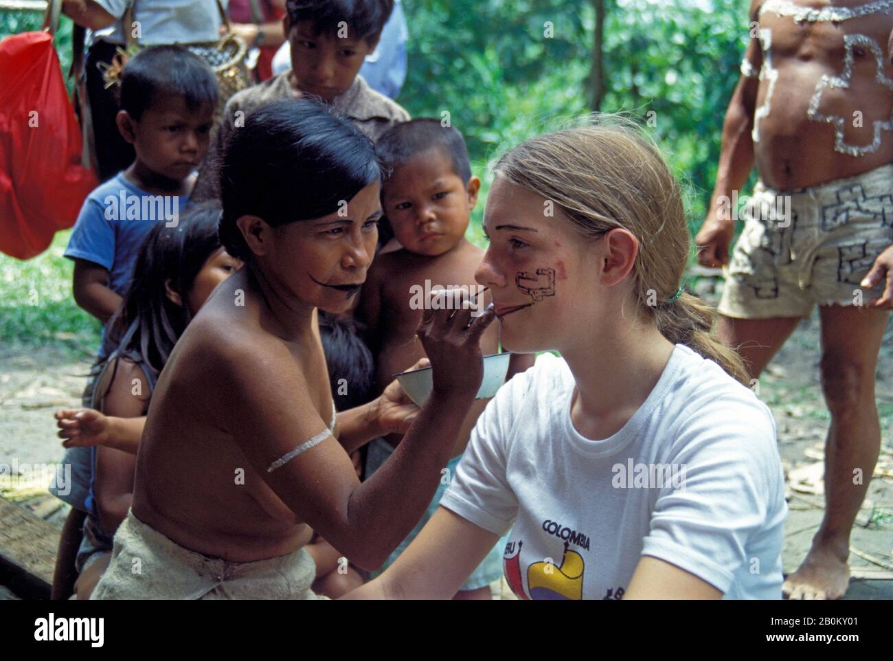 AMAZON, PÉROU, BORA INDIENS AVEC FILLE TOURISTE AYANT LE VISAGE PEINT AVEC DES COLORANTS DE PLANTES TRADITIONNELS Banque D'Images