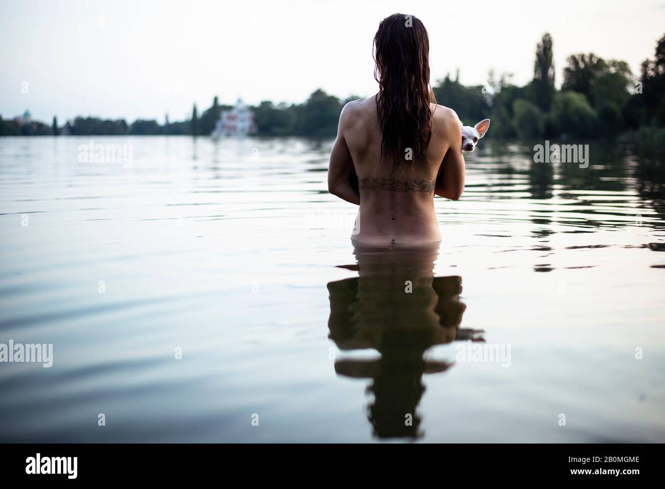 vue arrière d'une femme forte tenant un petit chien dans le lac naturel de berlin Banque D'Images