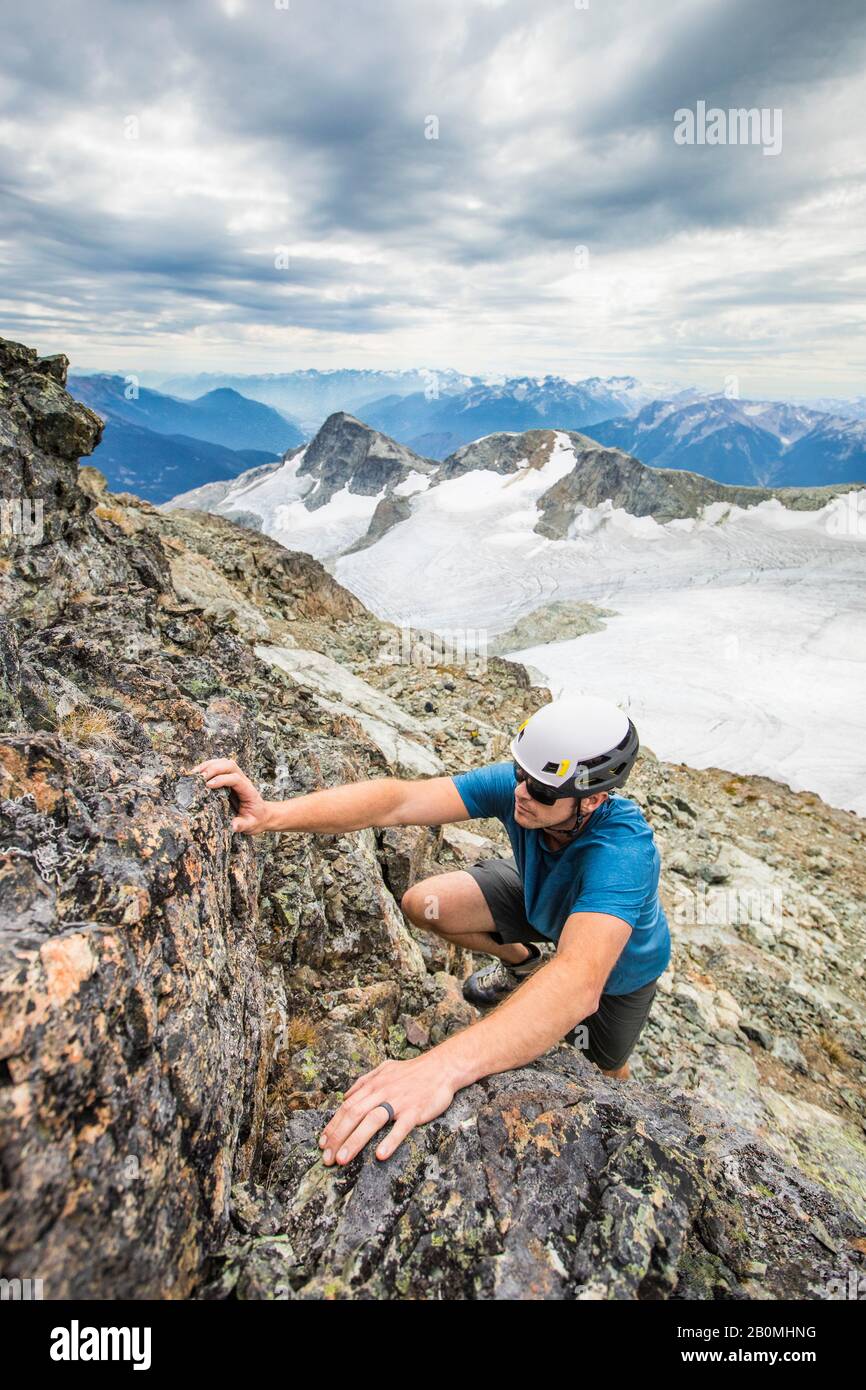 Le grimpeur portant un casque se démène vers le sommet d'une montagne. Banque D'Images