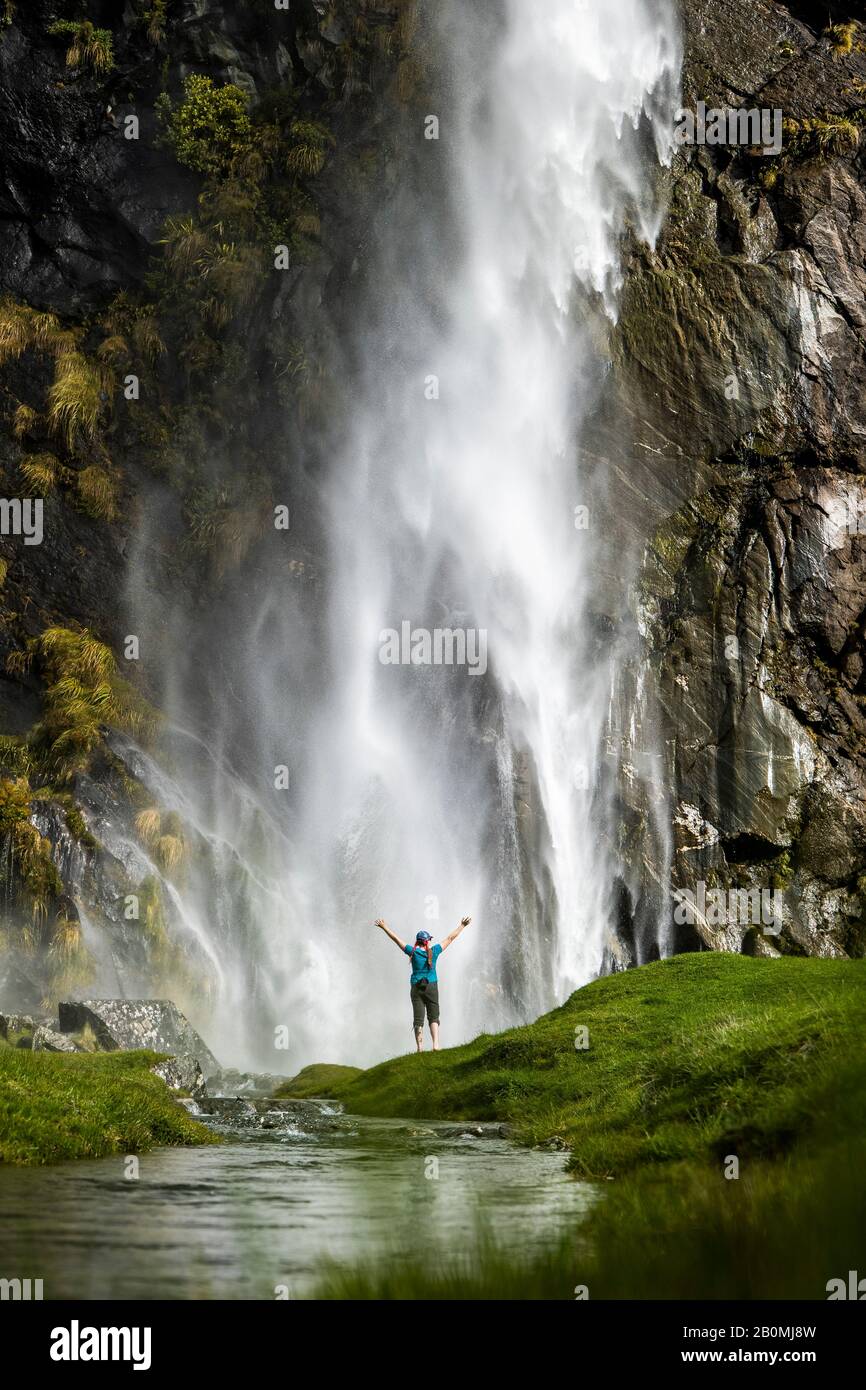 Figure debout devant un jet en cascade, dans un paysage de nature verte Banque D'Images