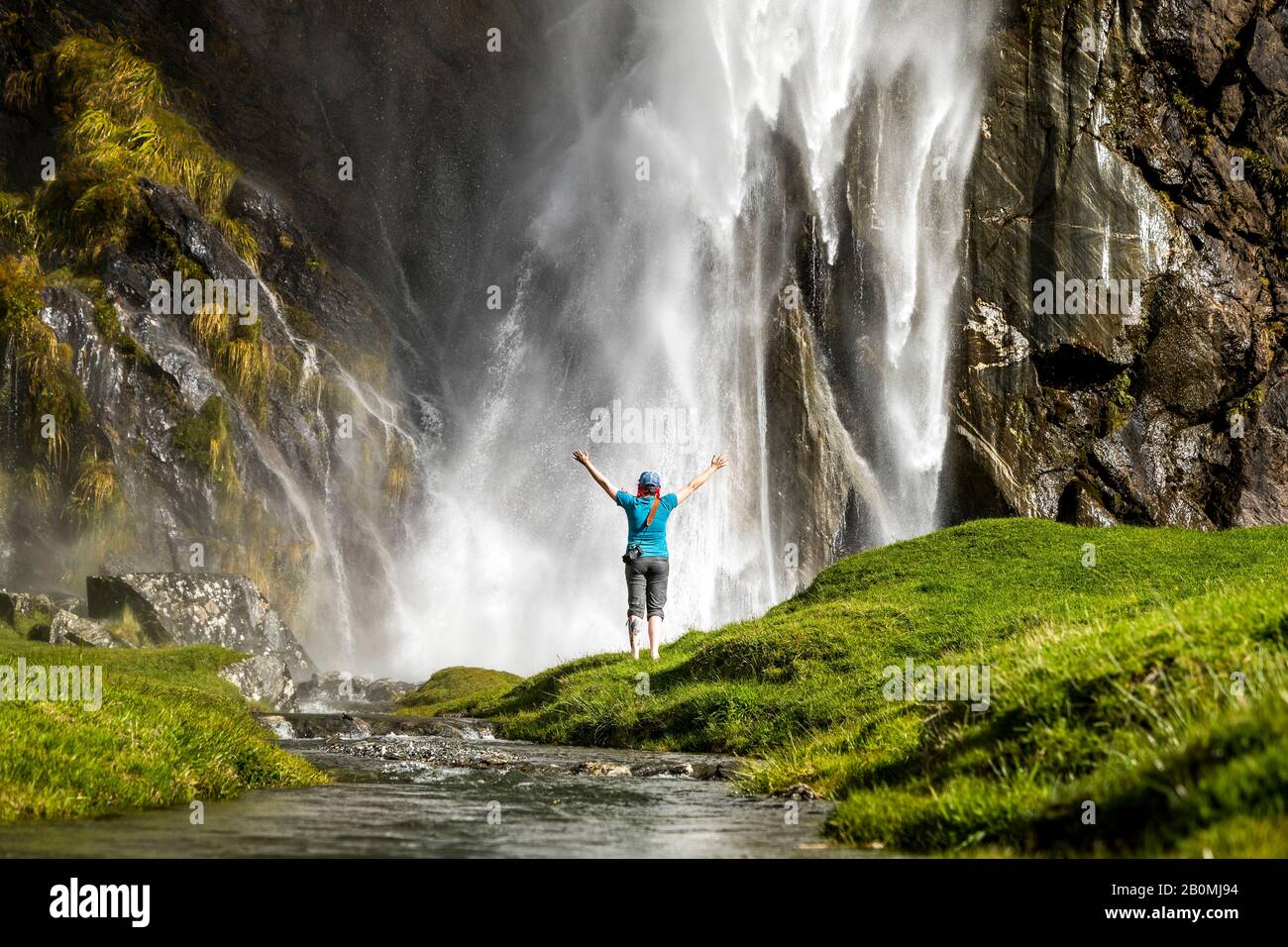 Figure debout devant un jet en cascade, dans un paysage de nature verte Banque D'Images