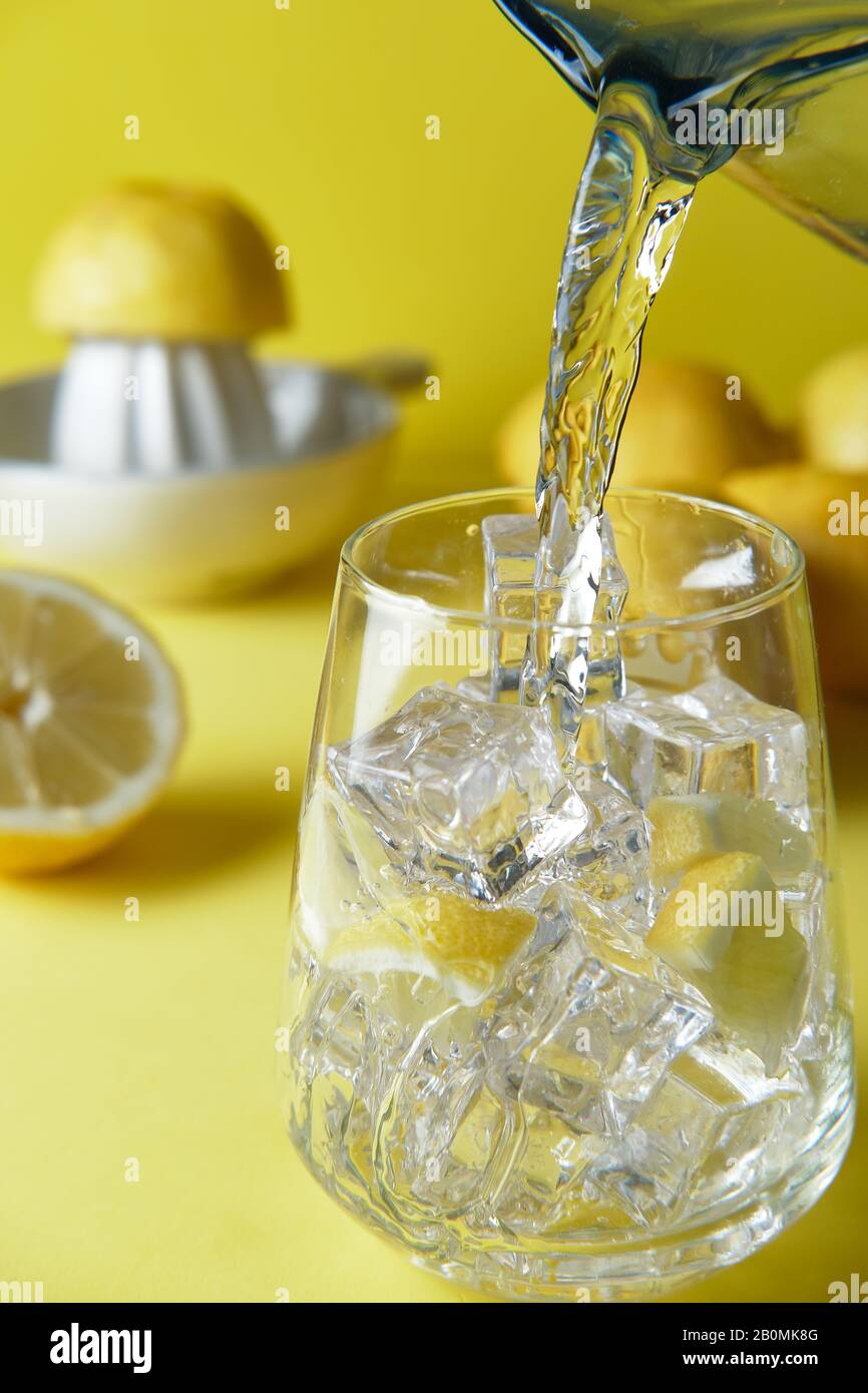 verser l'eau dans un verre avec de la glace pour faire de l'eau de citron Banque D'Images