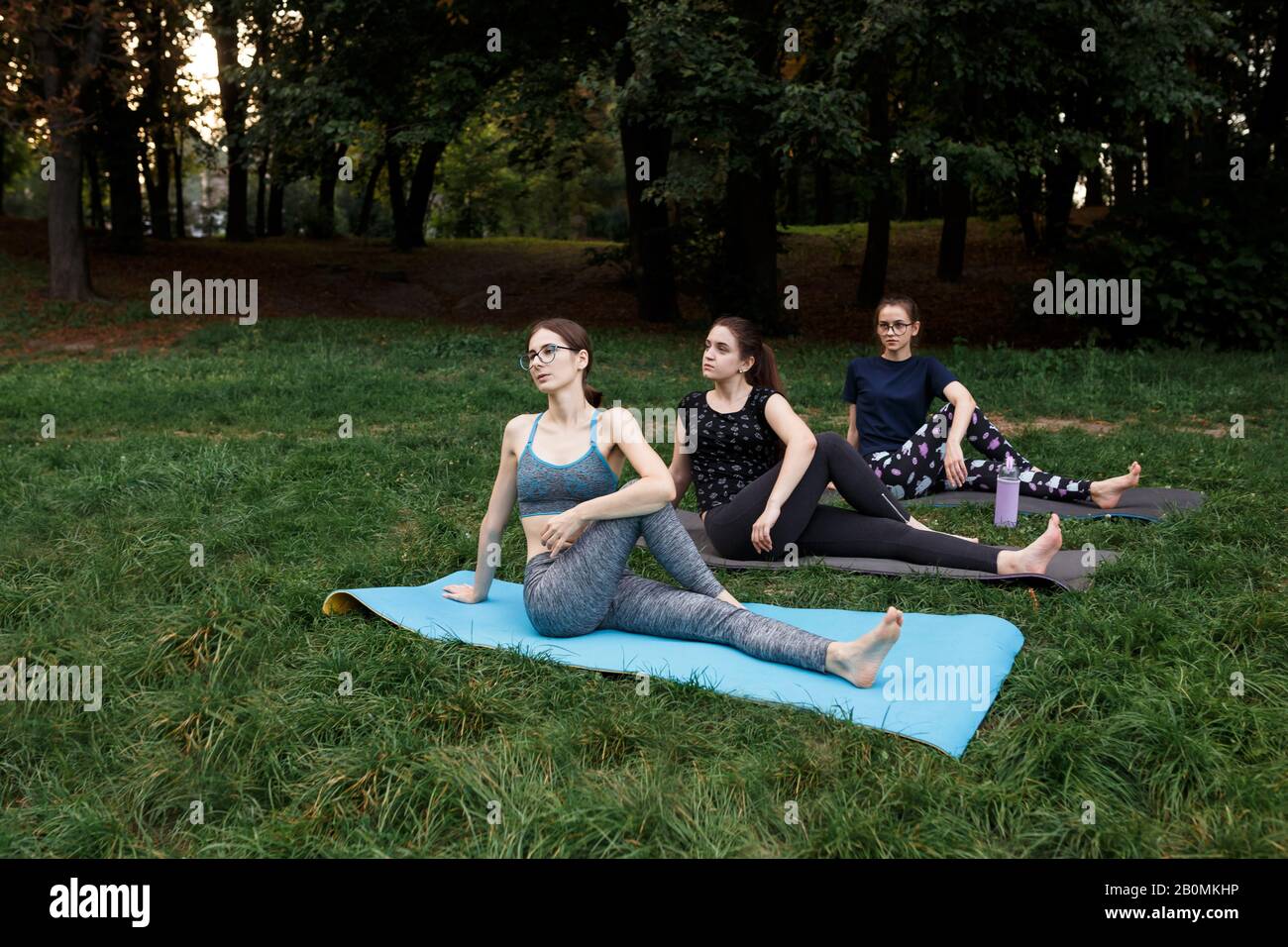 Les filles décontractées font du yoga dans le parc sur la moquette Banque D'Images