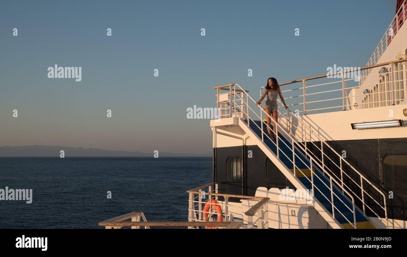 Une jeune fille en short debout sur l'escalier bleu sur le ferry à bord d'un ferry à destination de Lesvos en Grèce Banque D'Images