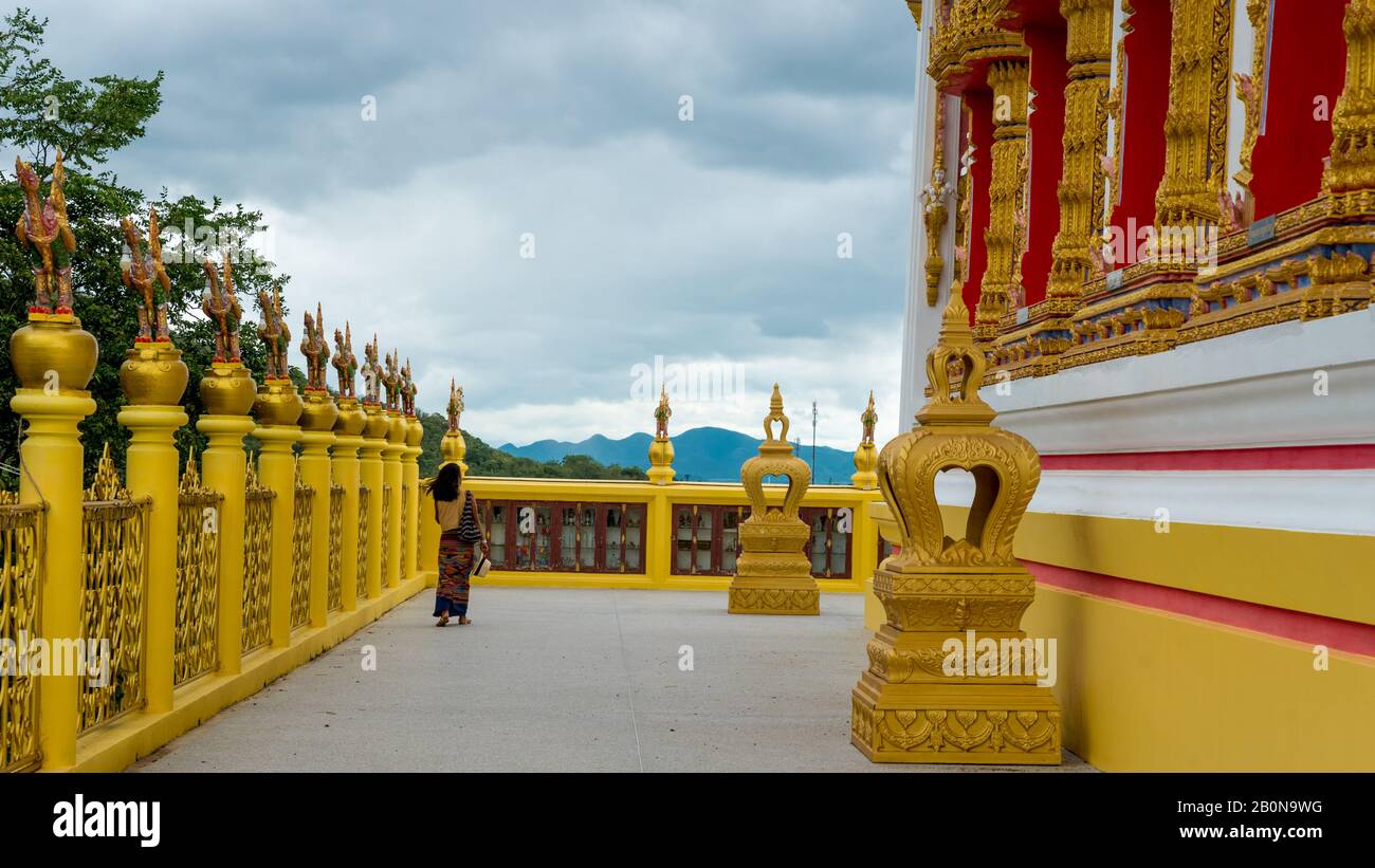 Femme dans sarong marchant le long du mur de wat dans Pak Nam Pranburi Thaïlande. Banque D'Images