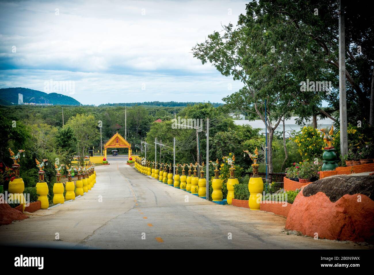 Entrée au wat bordée de statues sur des pedestals jaunes à Pak Nam Pran, Pranburi Thaïlande Banque D'Images