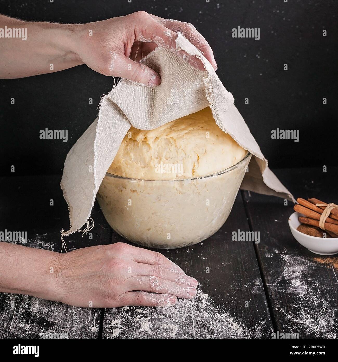 Les mains féminines tiennent une serviette sur une pâtisserie fermentée maison pour les petits pains. Gros plan. Recette étape par étape Banque D'Images
